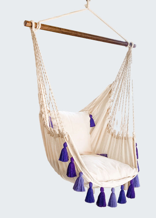 White hanging chair with purple tassels in a room with decorative elements.
