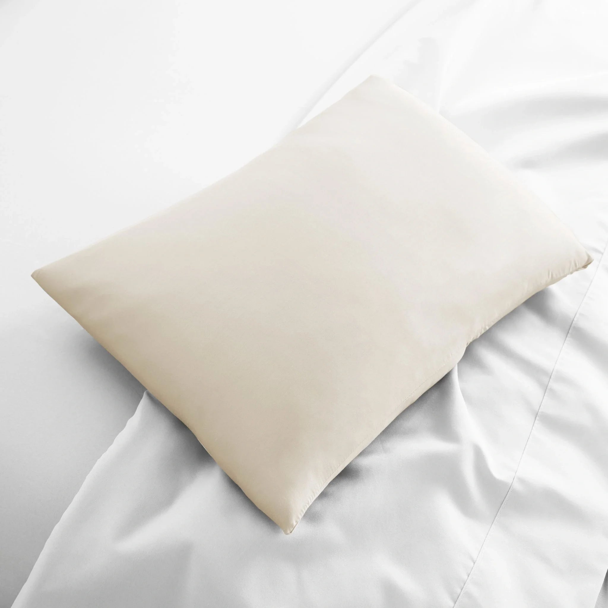 Beige pillow on a white bed