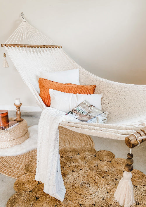 Cozy indoor setting with a hammock, pillows, and a magazine on a neutral background