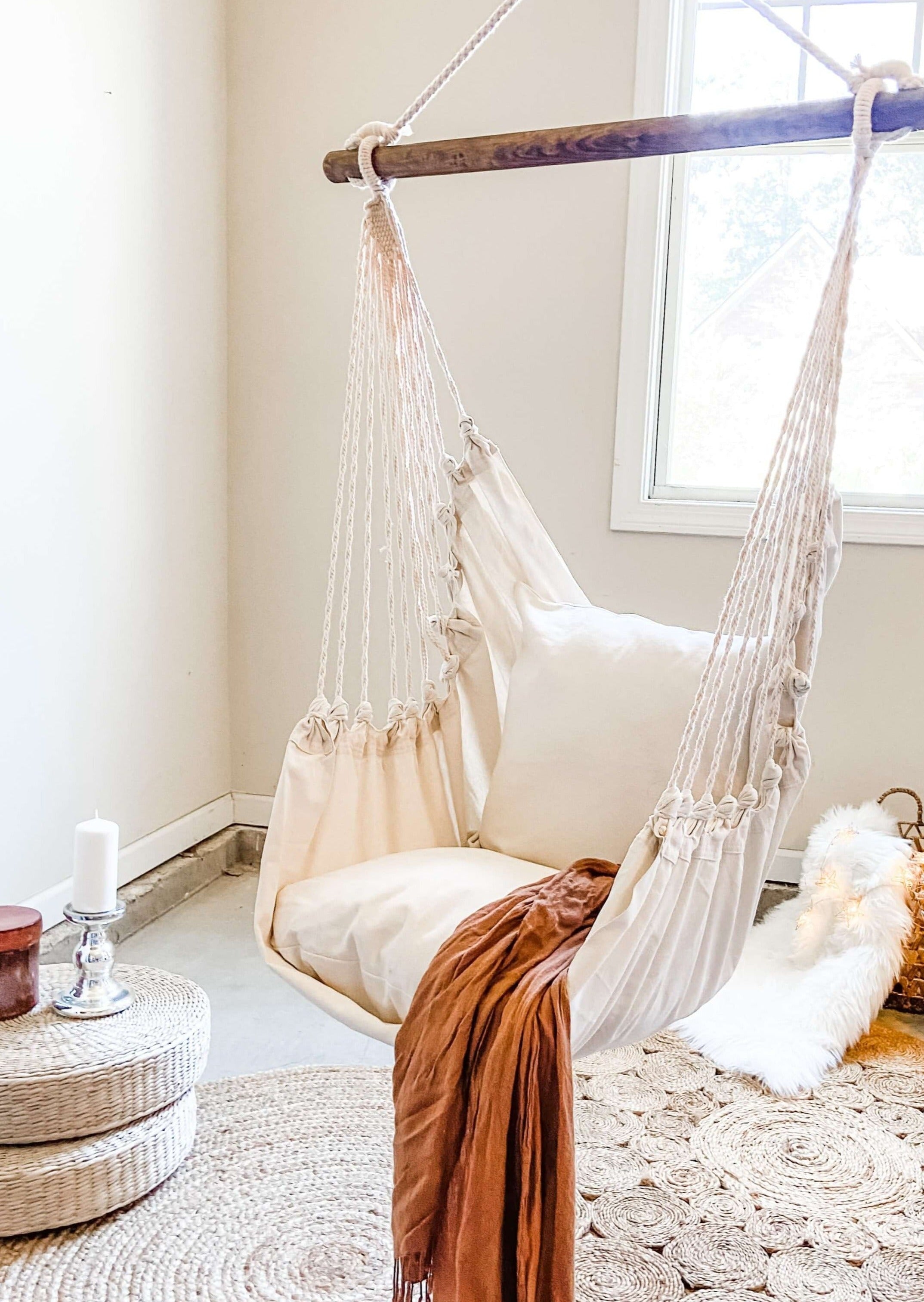 Hanging chair with a pillow and blanket in a cozy room.