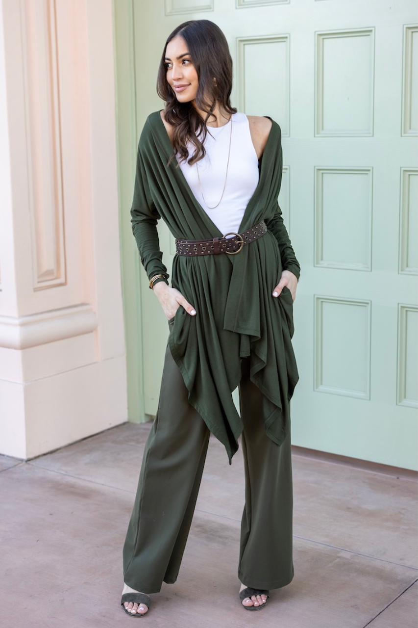 Woman wearing a green outfit with a white top, standing in front of a light green door.