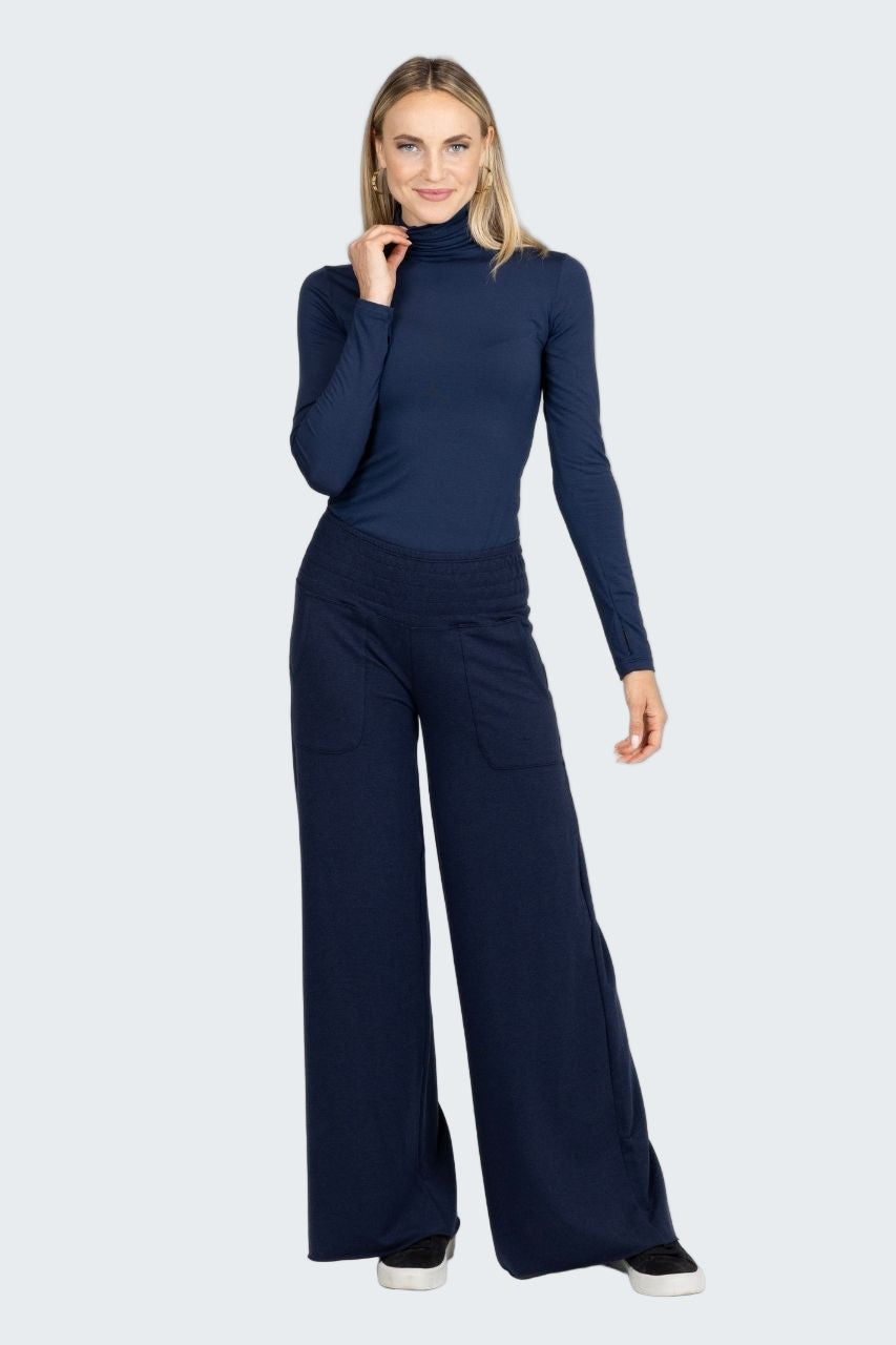 Woman wearing a navy blue turtleneck and wide-leg pants on a white background