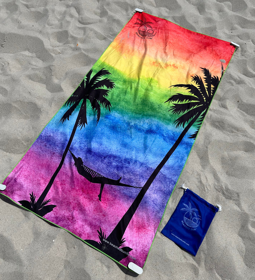 Colorful towel with palm tree and hammock design on sandy surface