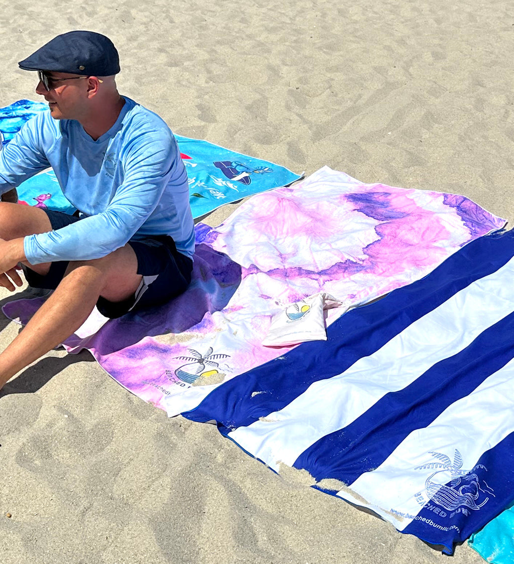 Man sitting on a colorful beach towel on sand