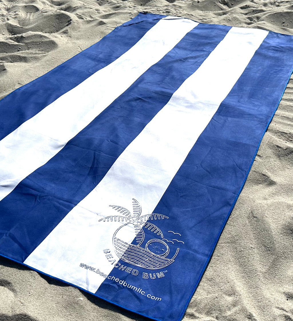 Blue and white striped towel with a logo on a sandy surface