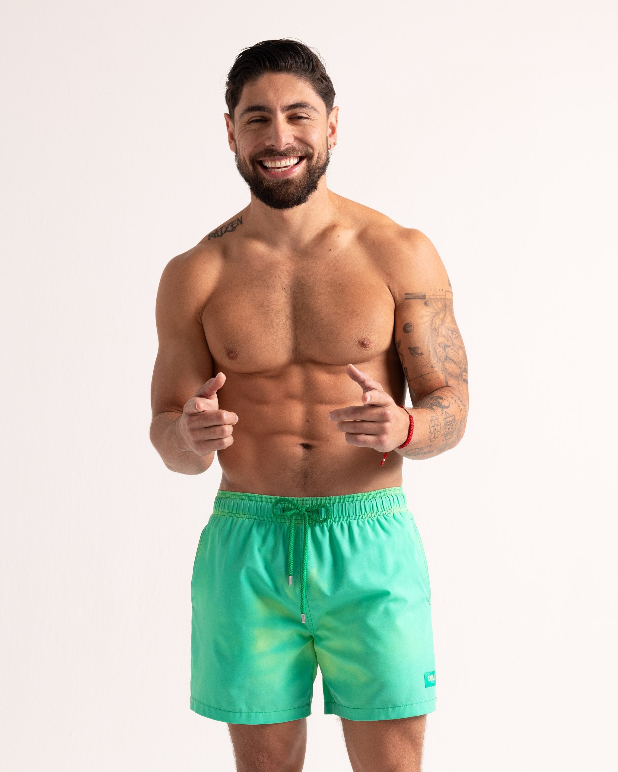Man wearing green swim shorts on a plain background