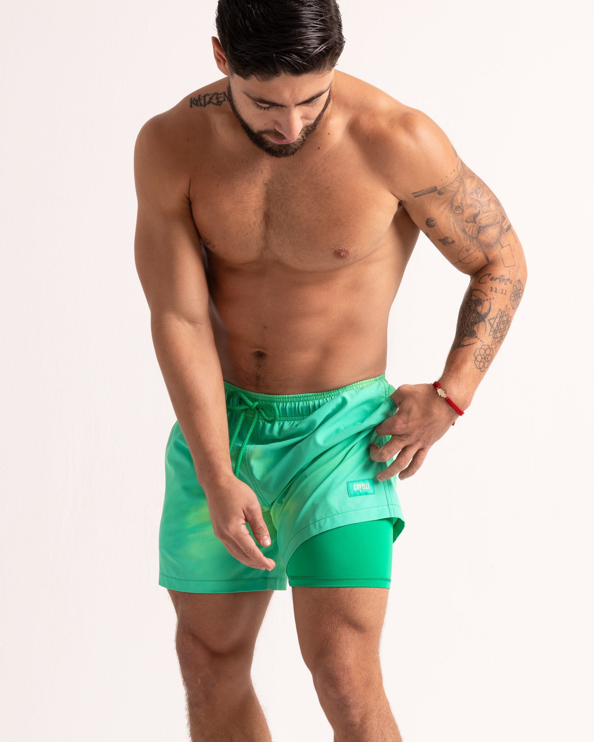 Man wearing green swim shorts on a plain background
