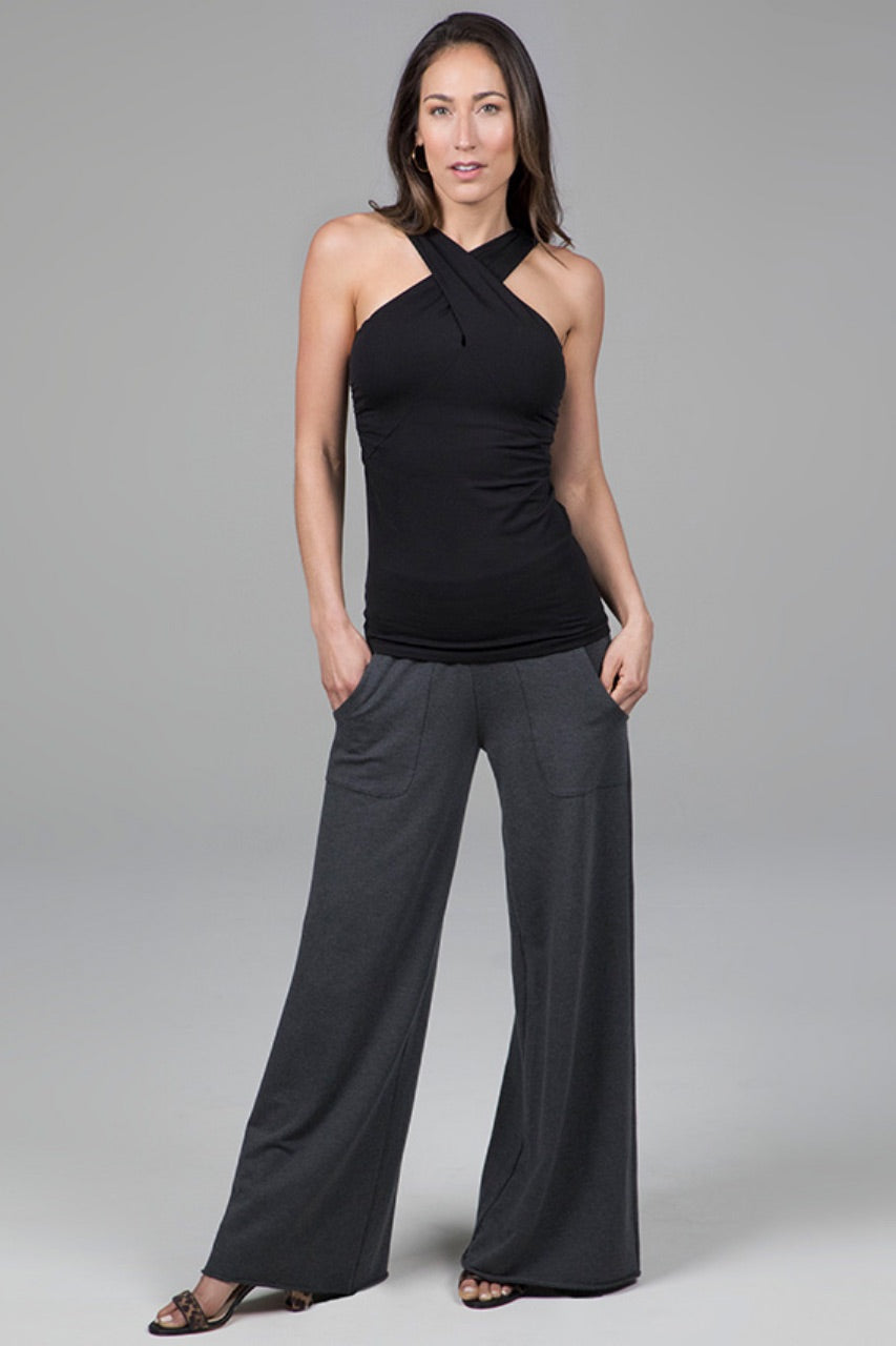 Woman wearing a black halter top and gray wide-leg pants on a gray background