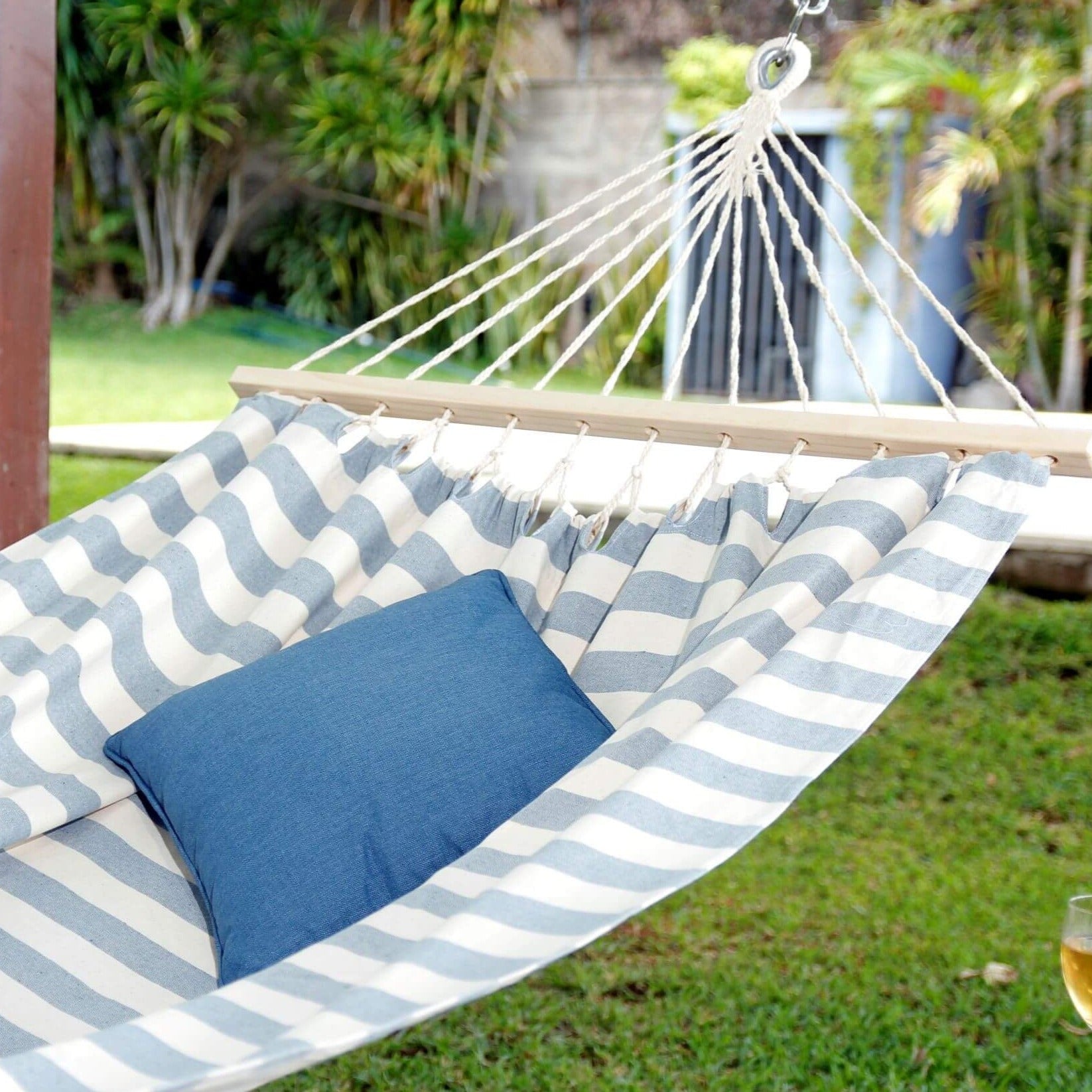 Striped hammock with a blue pillow in a garden setting