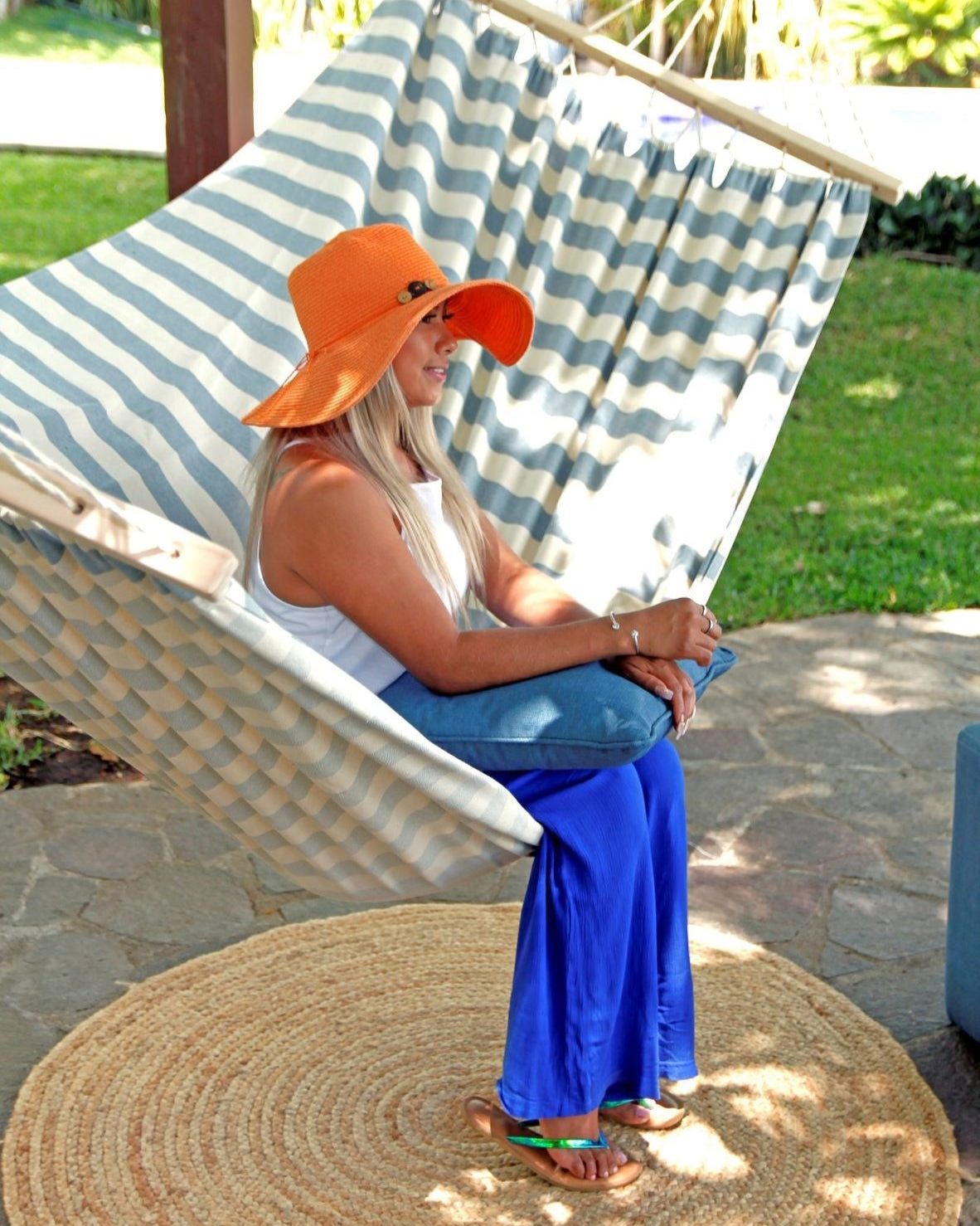 Woman sitting in a striped hammock on a patio