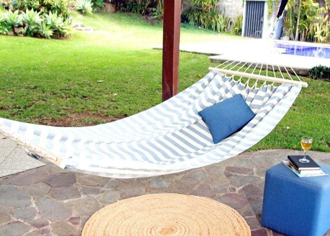 Hammock with a pillow on a patio area with a pool in the background