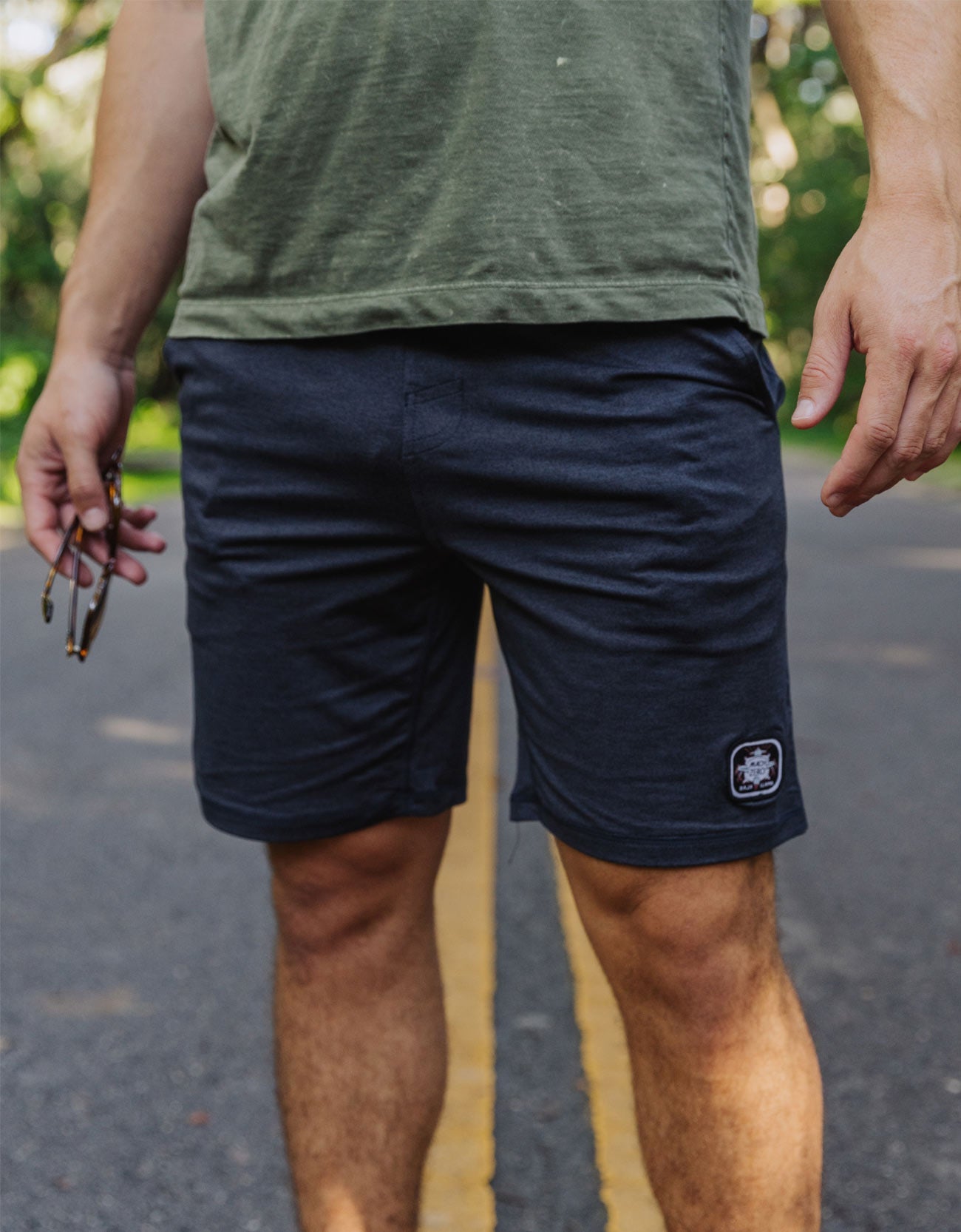 Person wearing navy shorts with a brand logo on a blurred outdoor background