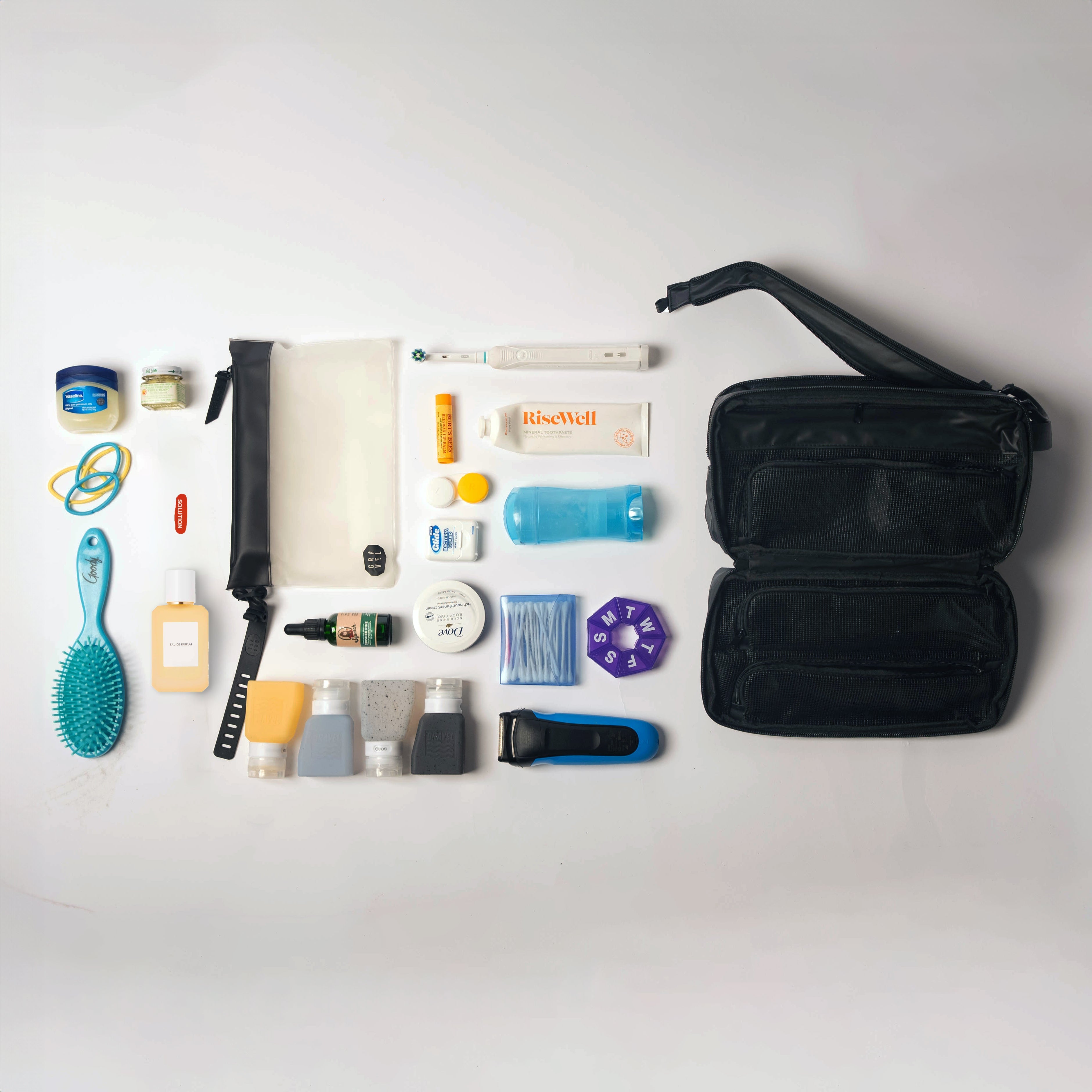 Collection of travel-sized products including a hairbrush, bottles, and a razor on a white background.