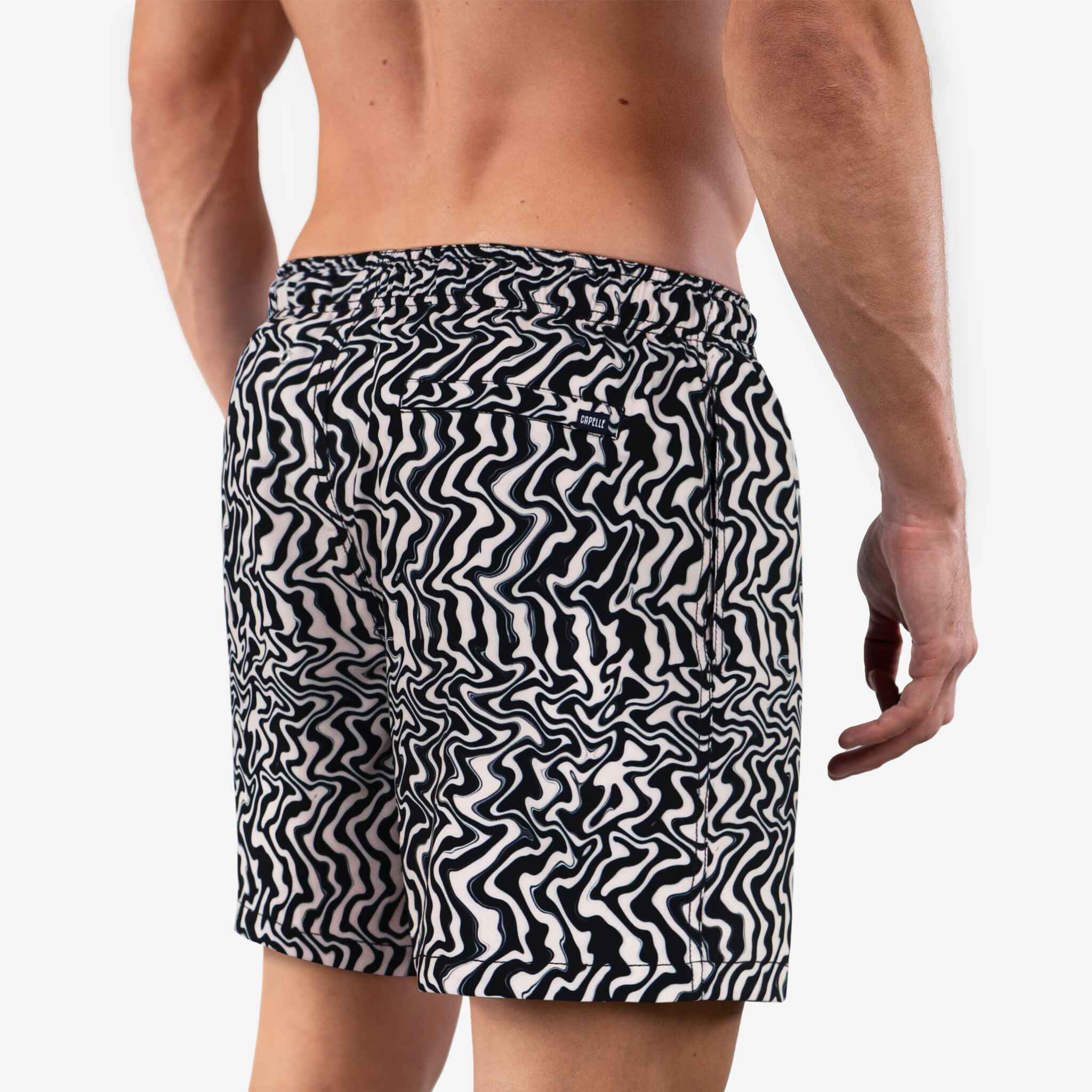 Person wearing black and white patterned swim shorts on a plain background