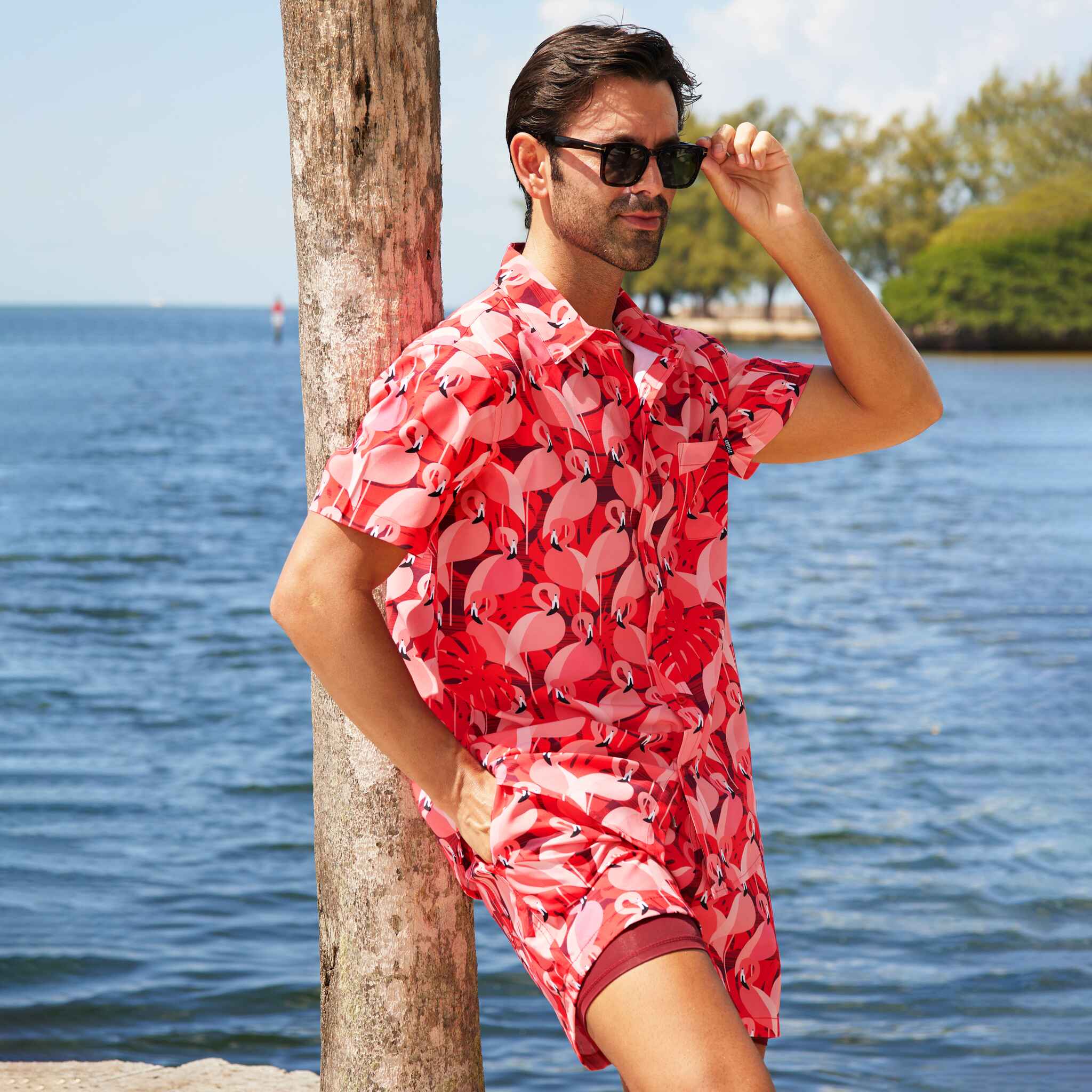 Man wearing a red floral shirt by the water