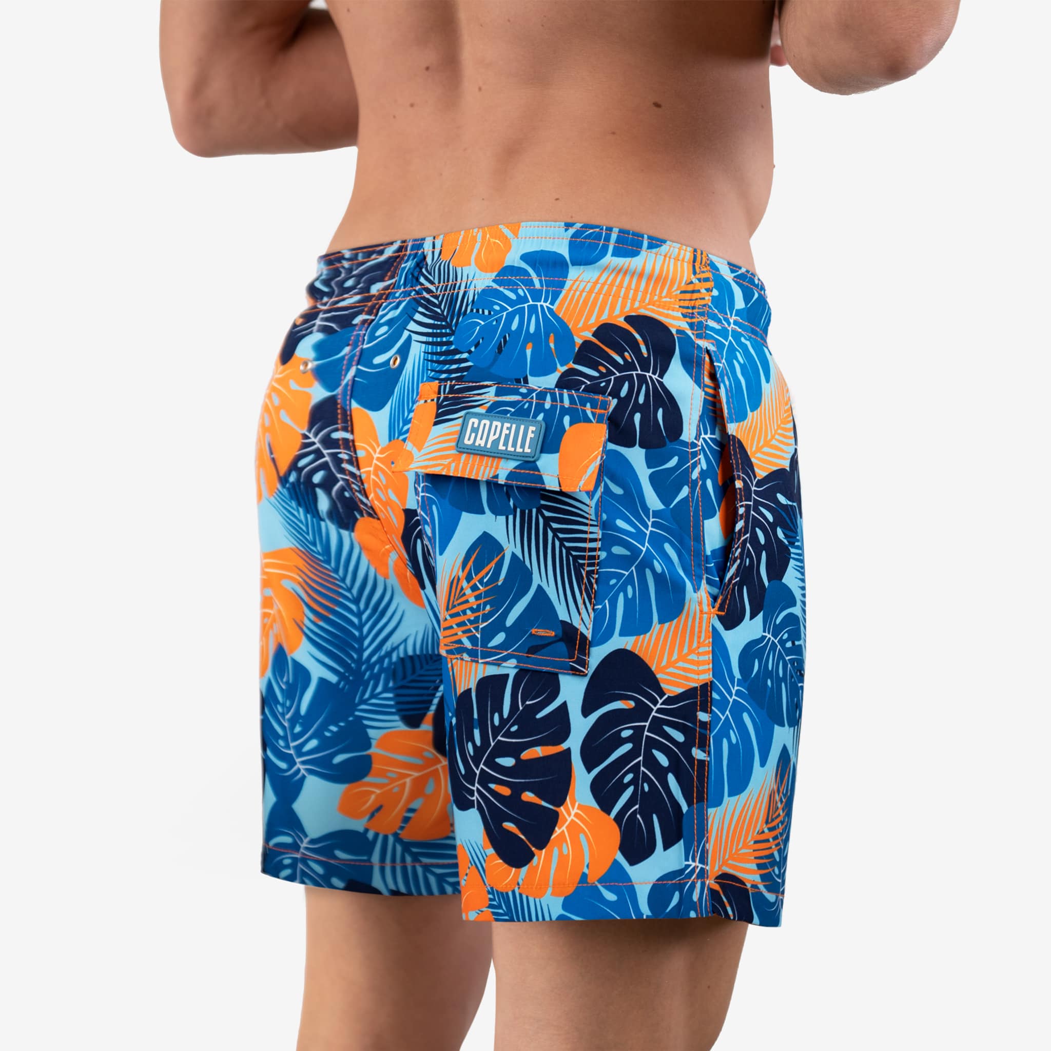 Tropical leaf patterned swim shorts on a white background