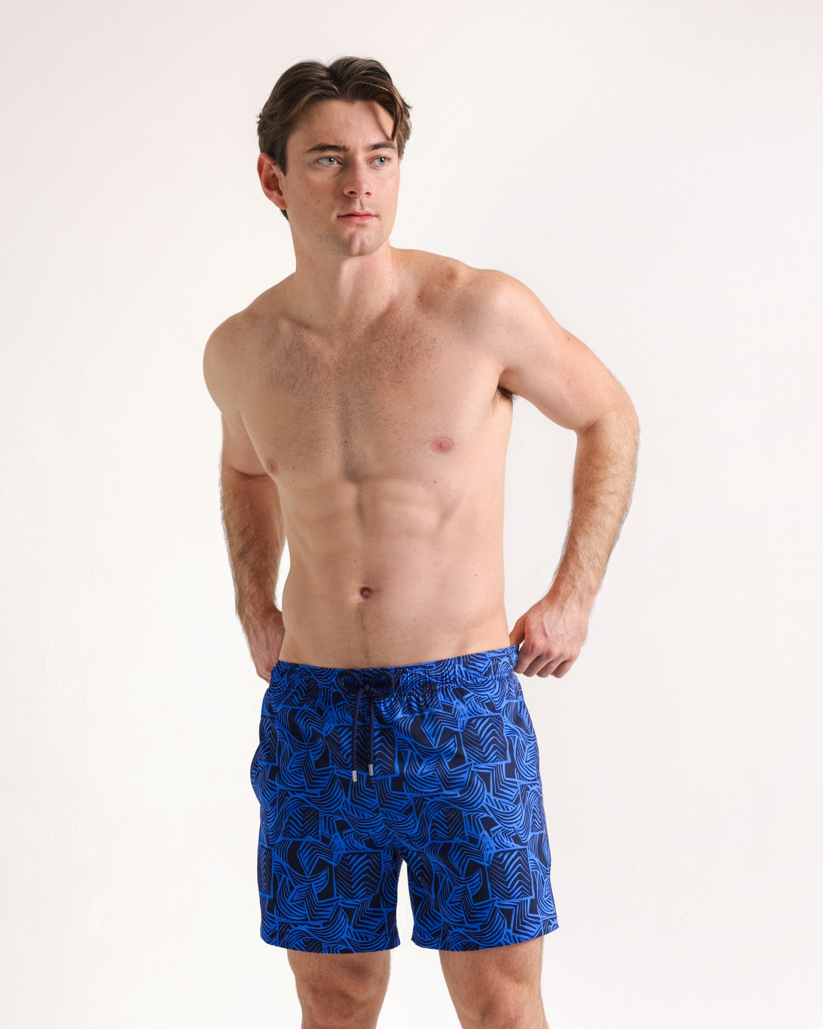 Man wearing blue patterned swim shorts on a white background