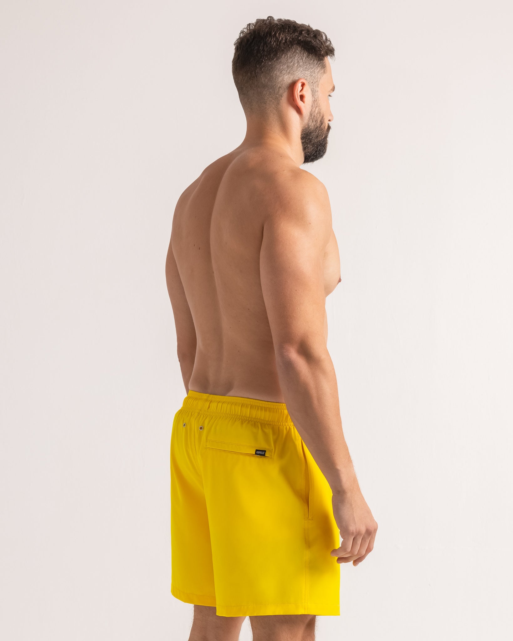 Man wearing yellow swim shorts on a white background
