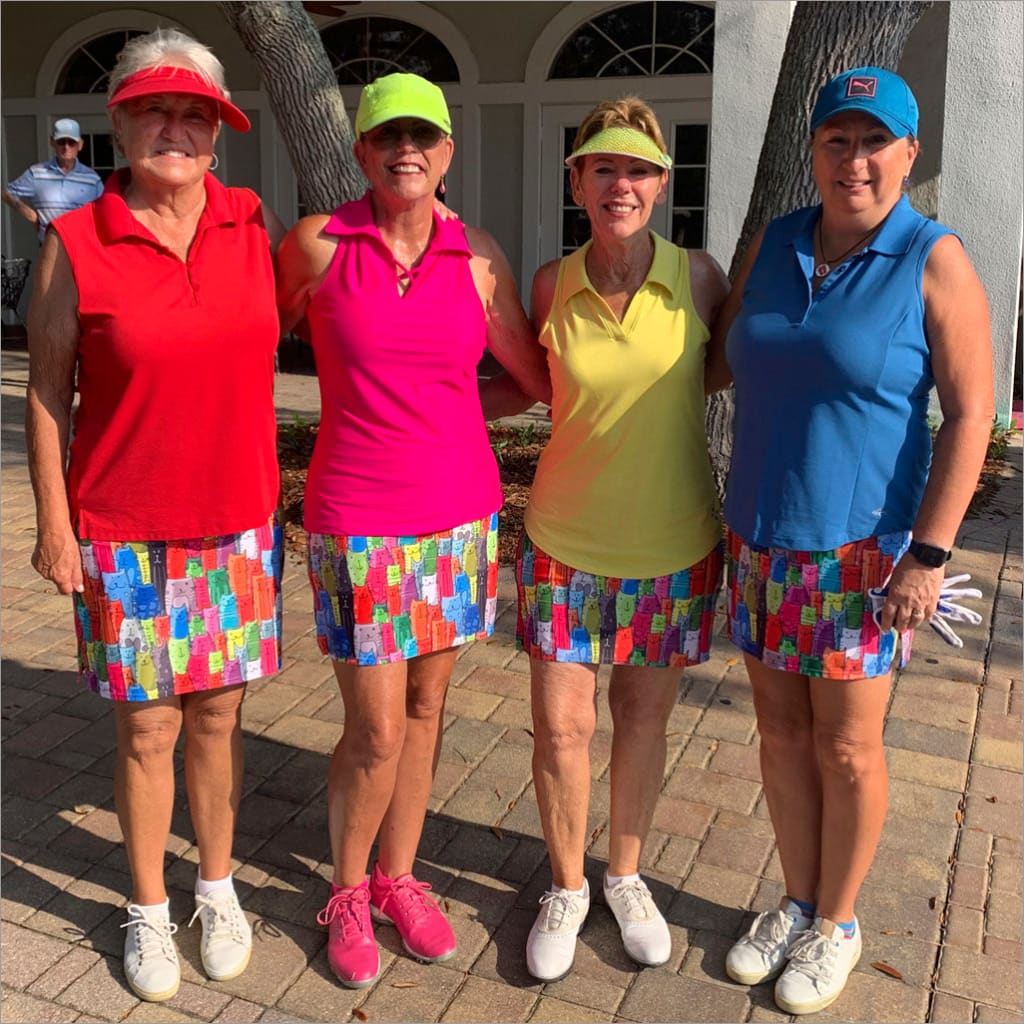 Four women in colorful outfits standing together outdoors.
