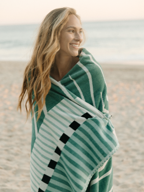 Woman wrapped in a green and white patterned towel on a beach