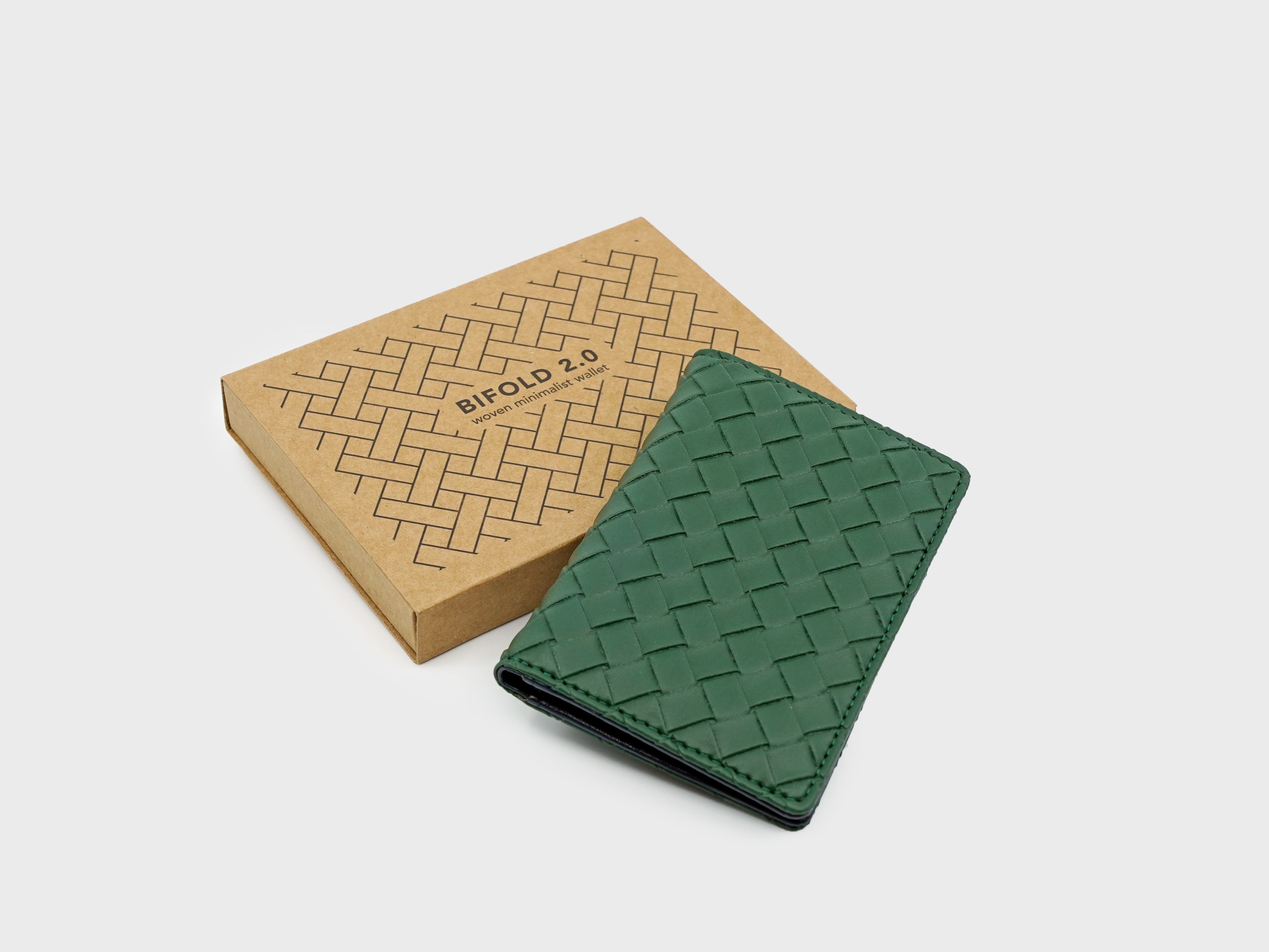 Green woven leather cardholder with a matching box on a light gray background