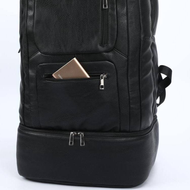 Black leather backpack with a pocket containing a phone on a white background