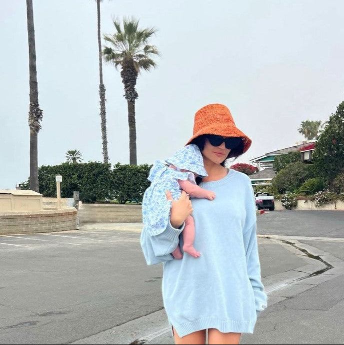 Woman holding a baby outdoors with palm trees in the background