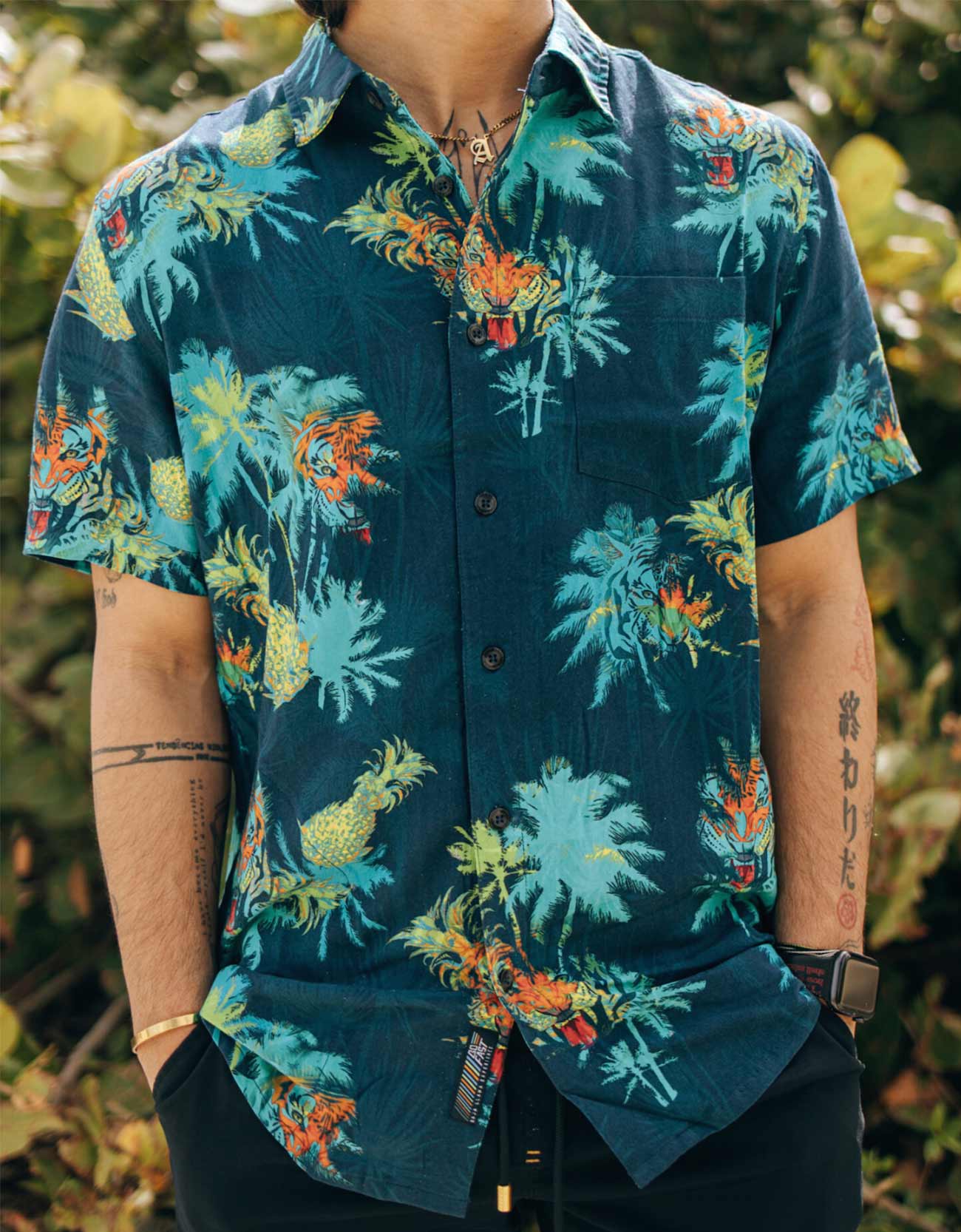 Person wearing a colorful tropical patterned shirt with a blurred natural background