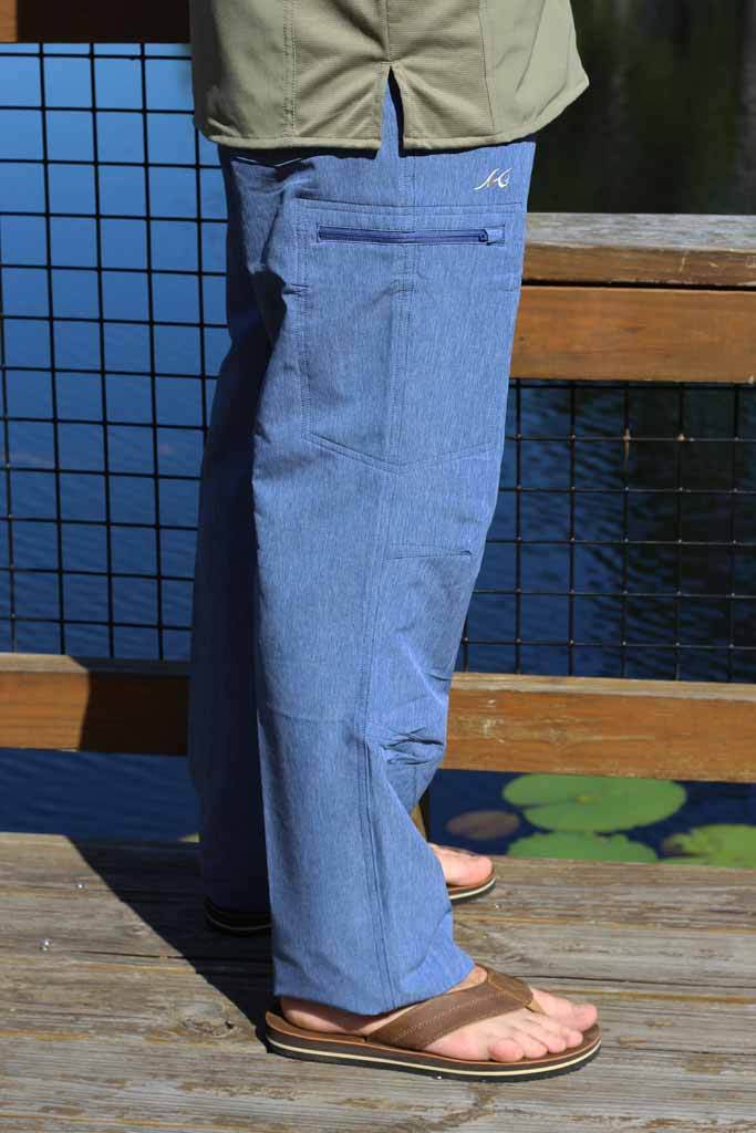 Person wearing blue pants and brown sandals standing on a wooden deck with a blue tiled wall in the background.