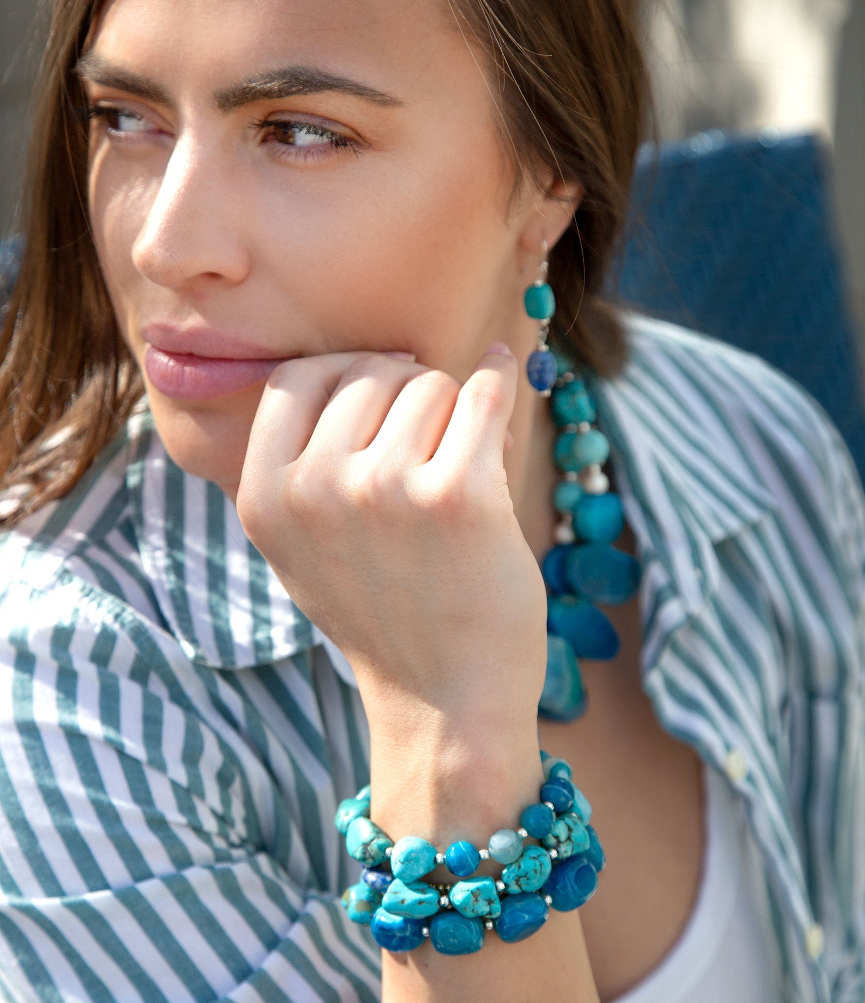 Woman wearing turquoise beaded bracelet and earrings outdoors