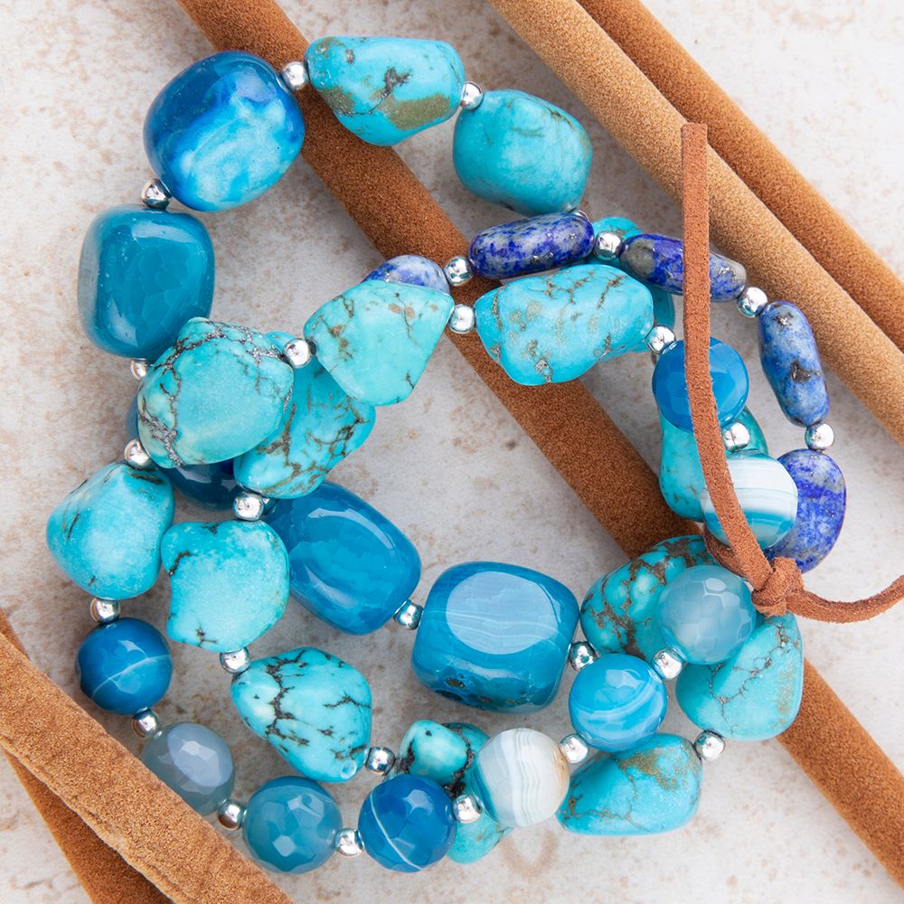Turquoise beaded bracelet with brown leather strap on a textured surface