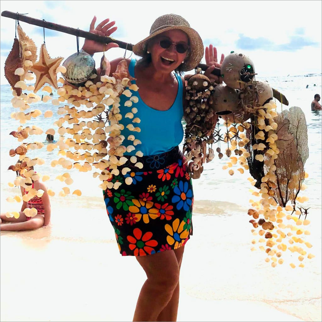 Woman on a beach holding shell decorations with ocean view