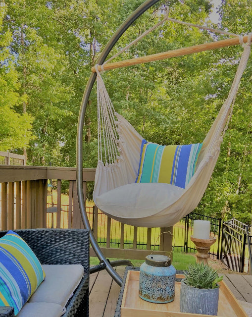 Hanging chair with striped cushion on a wooden deck surrounded by greenery