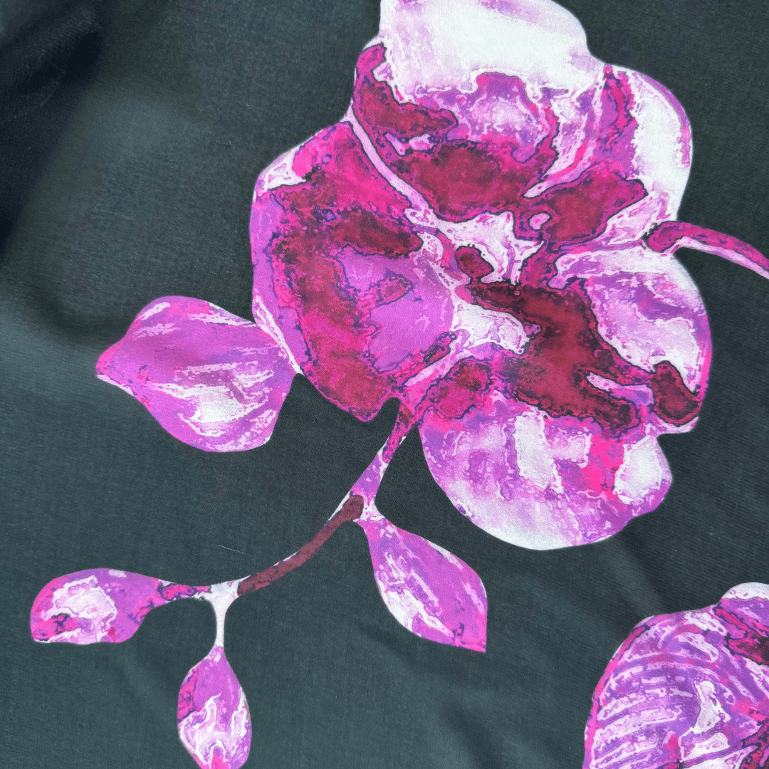 Close-up of a pink and purple floral design on a dark fabric background