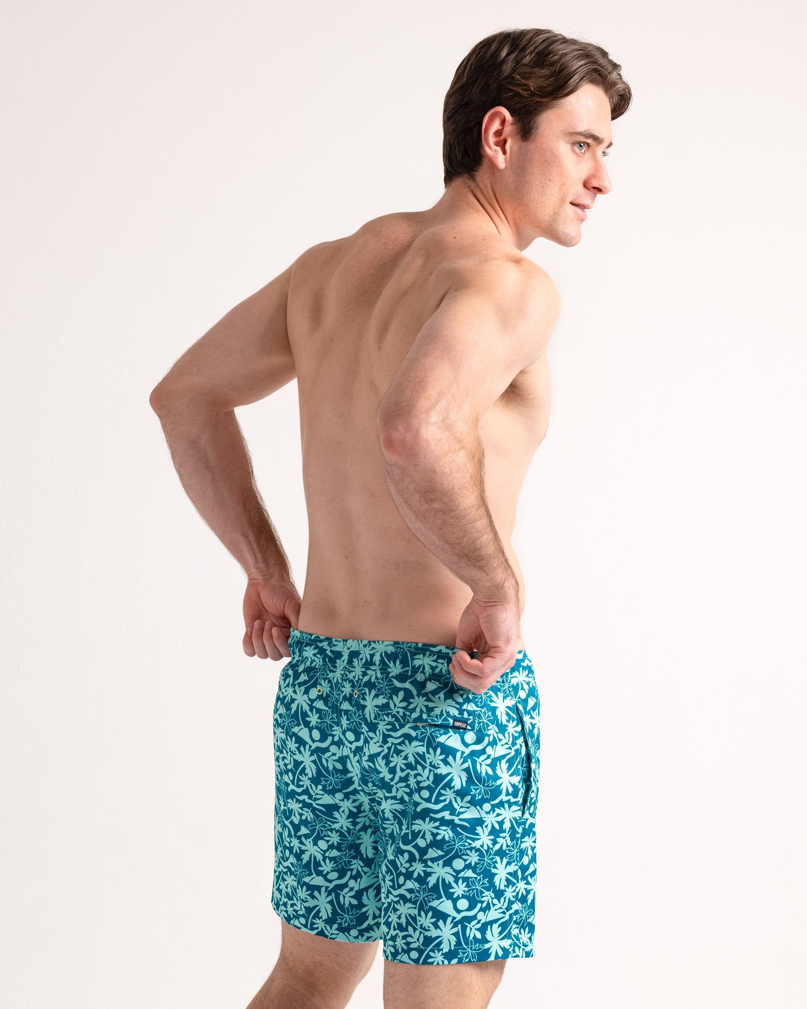 Man wearing blue floral swim shorts on a white background