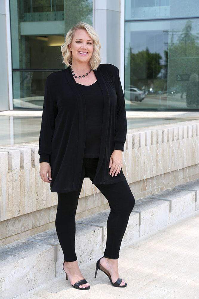 Woman in black outfit standing outdoors near a building