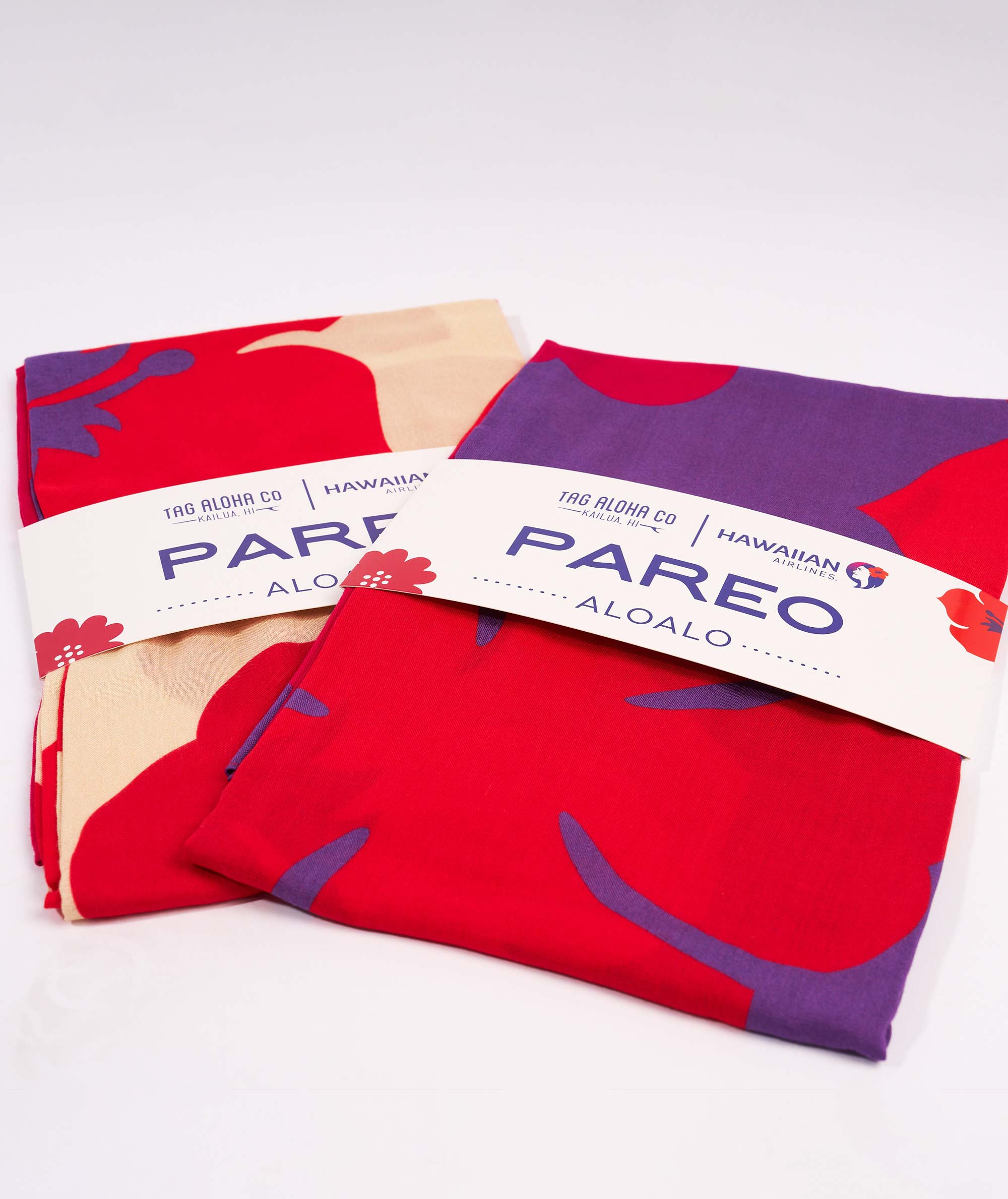 Two red and beige patterned pareos with 'Pareo Aloalo' branding on a white background.
