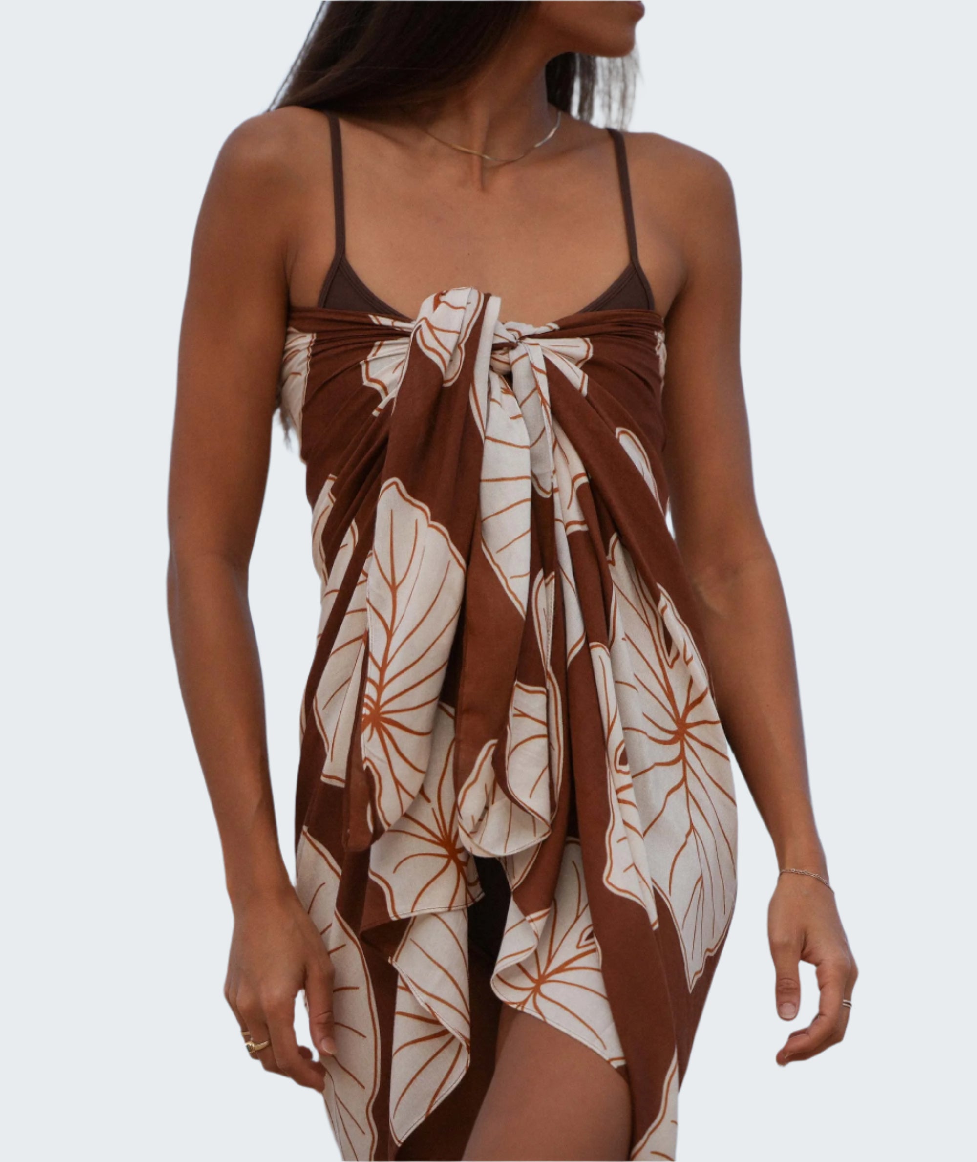 Woman wearing a brown and white floral dress against a blue sky.