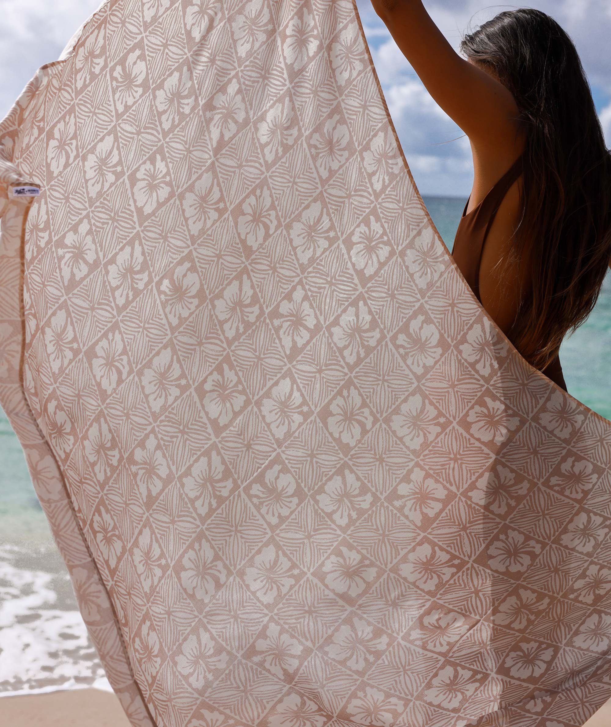 Person holding a patterned towel with ocean view