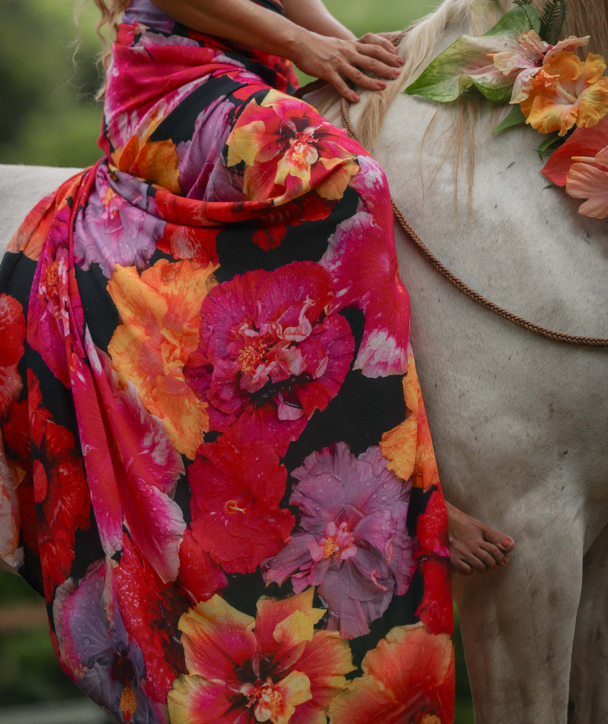 Person wearing a colorful floral dress standing next to a horse.