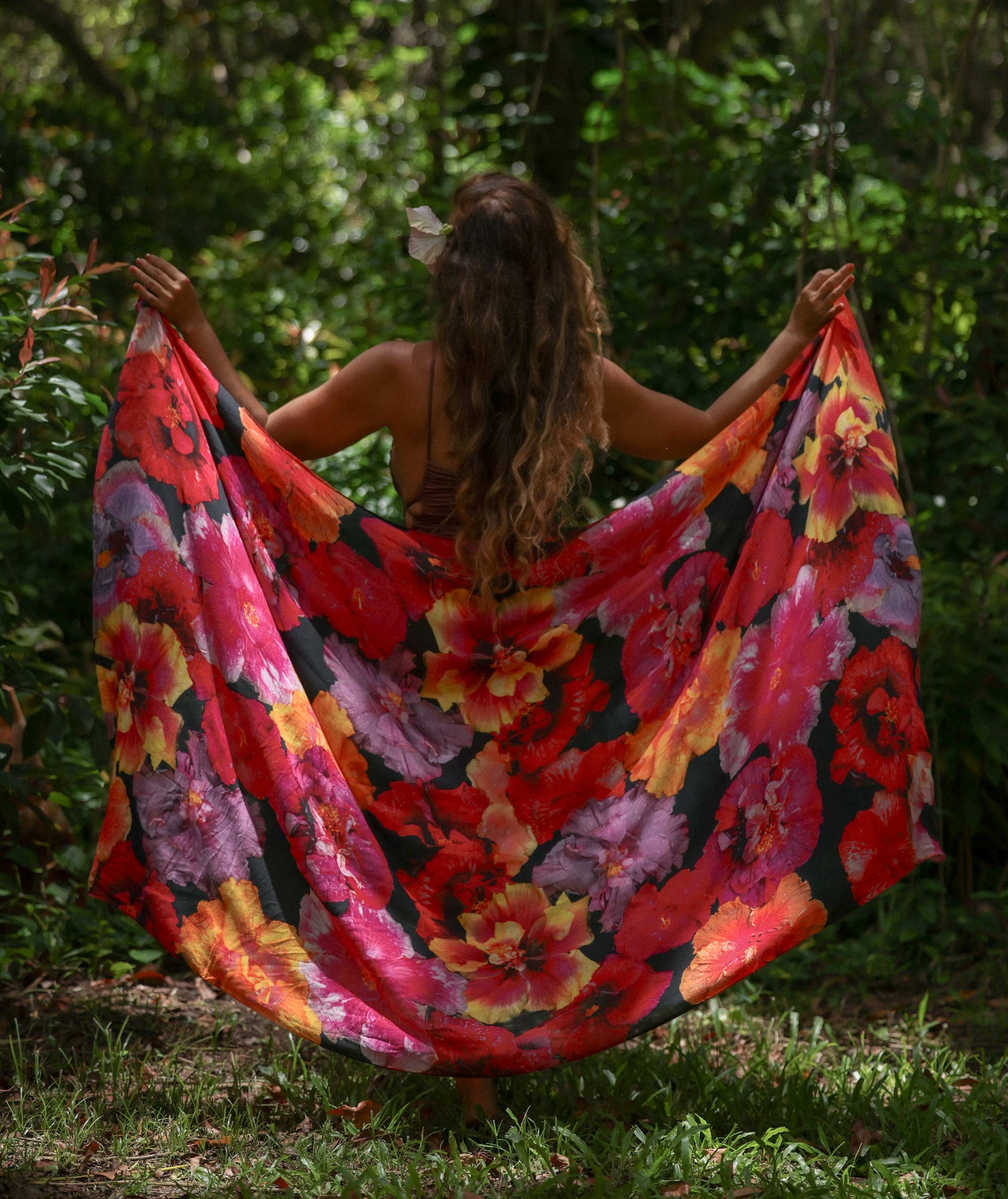 Woman holding a colorful floral scarf in a forest setting