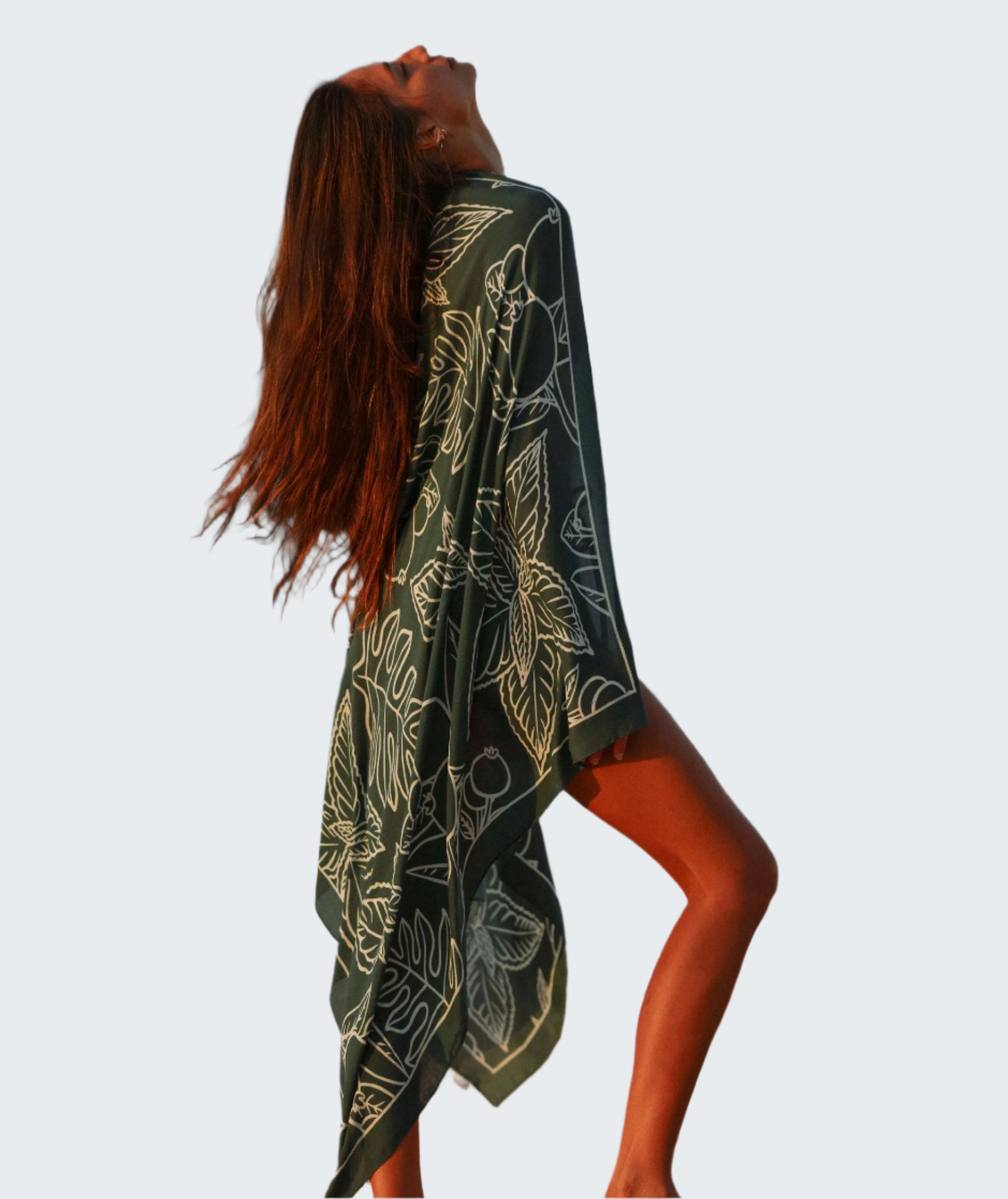 Woman standing on a beach with a black and white patterned towel draped over her shoulders.