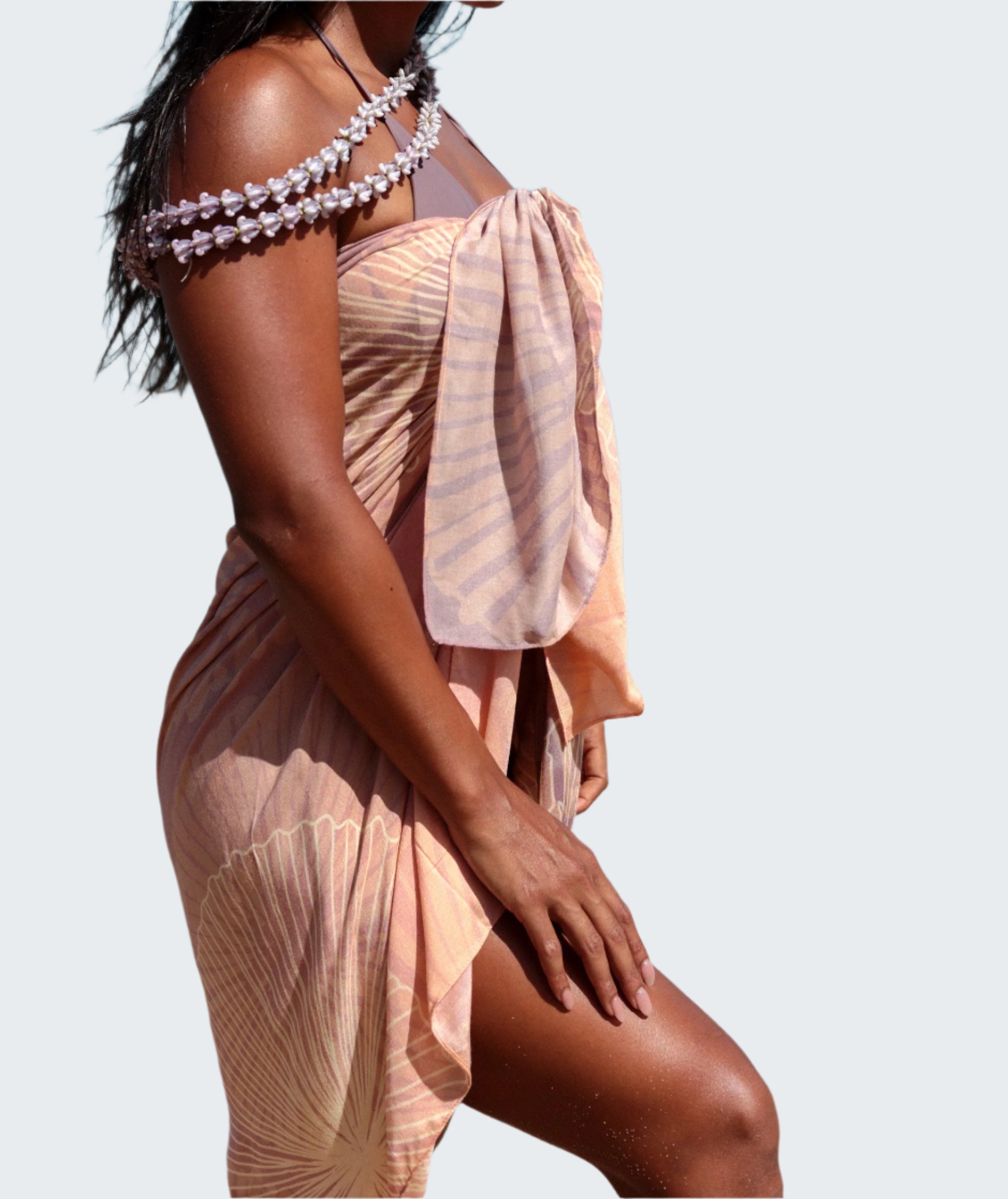 Woman in a peach dress standing on a beach with ocean and sky in the background