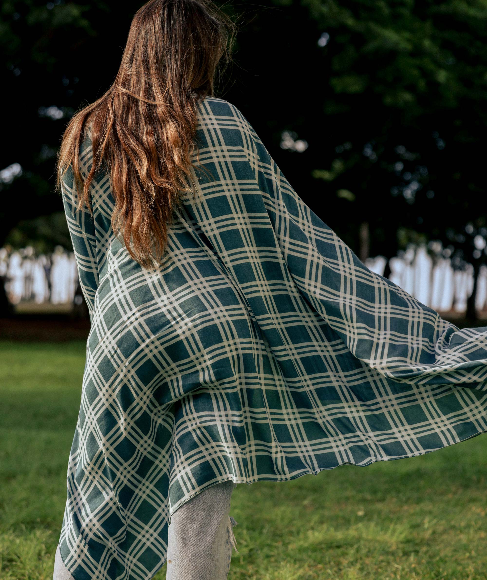 Person wearing a green and white plaid shawl in an outdoor setting