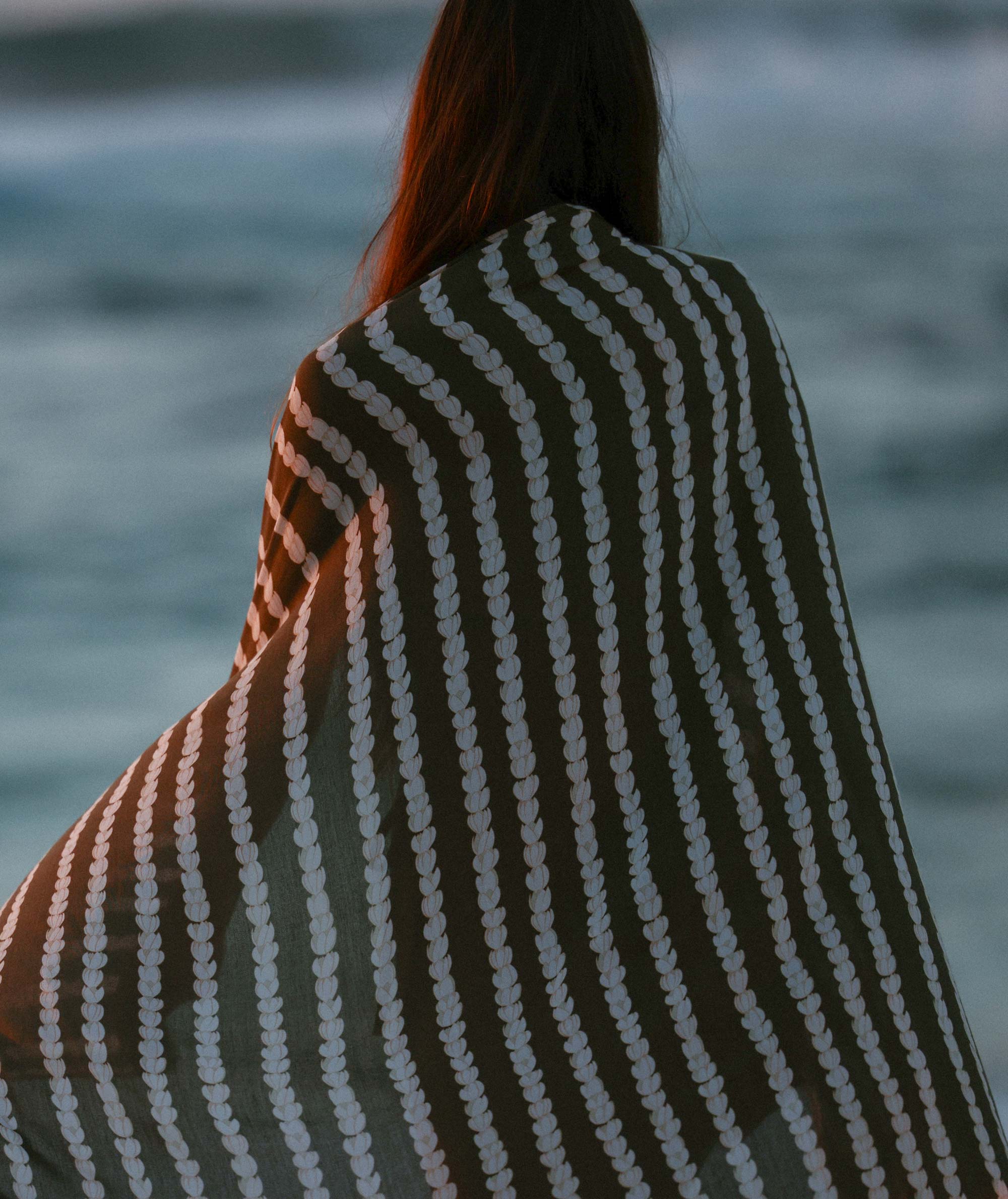Person wearing a striped garment with a blurred background of water