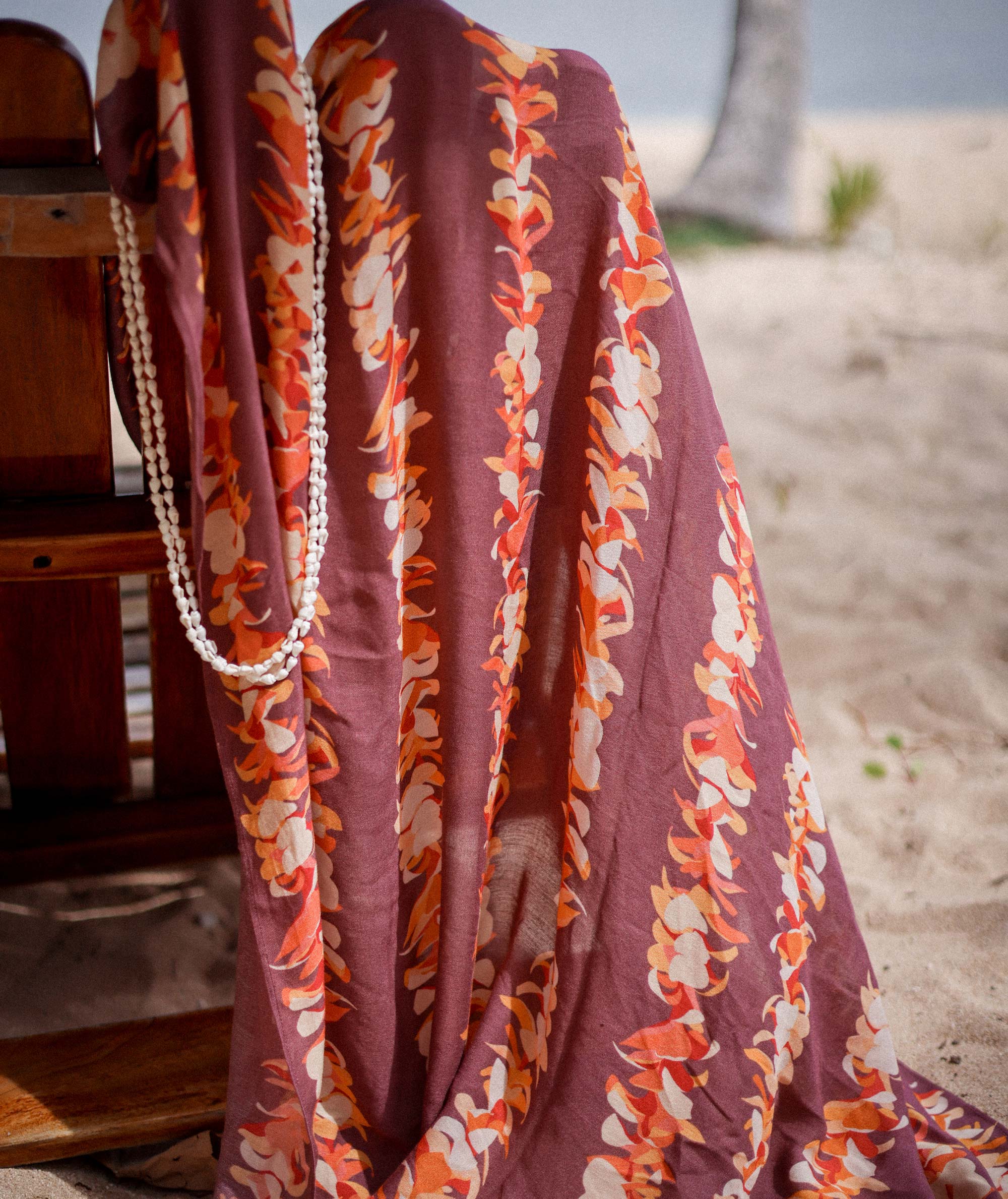 Floral patterned fabric draped over a chair on a beach.