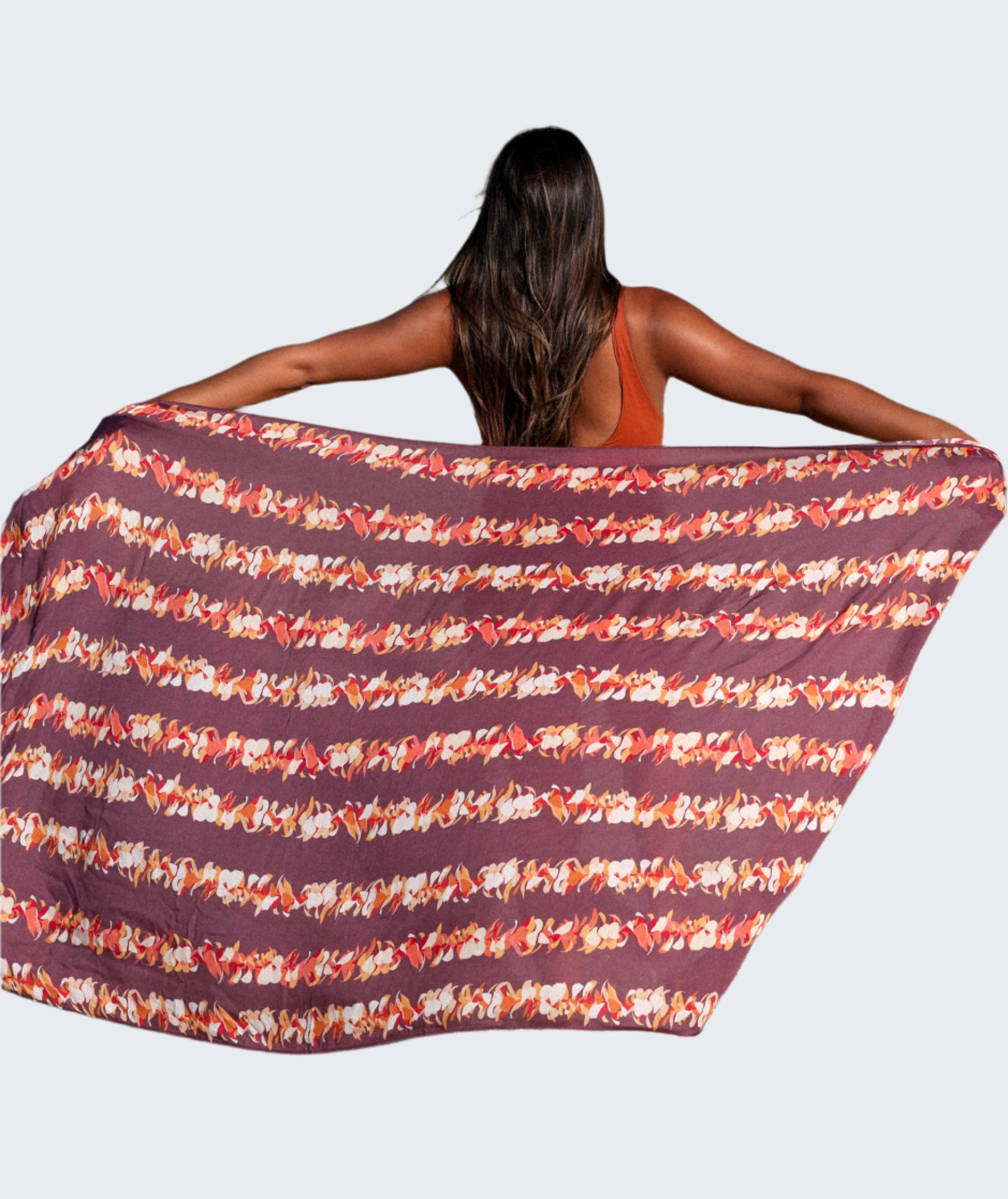 Woman on a beach with a patterned towel draped over her