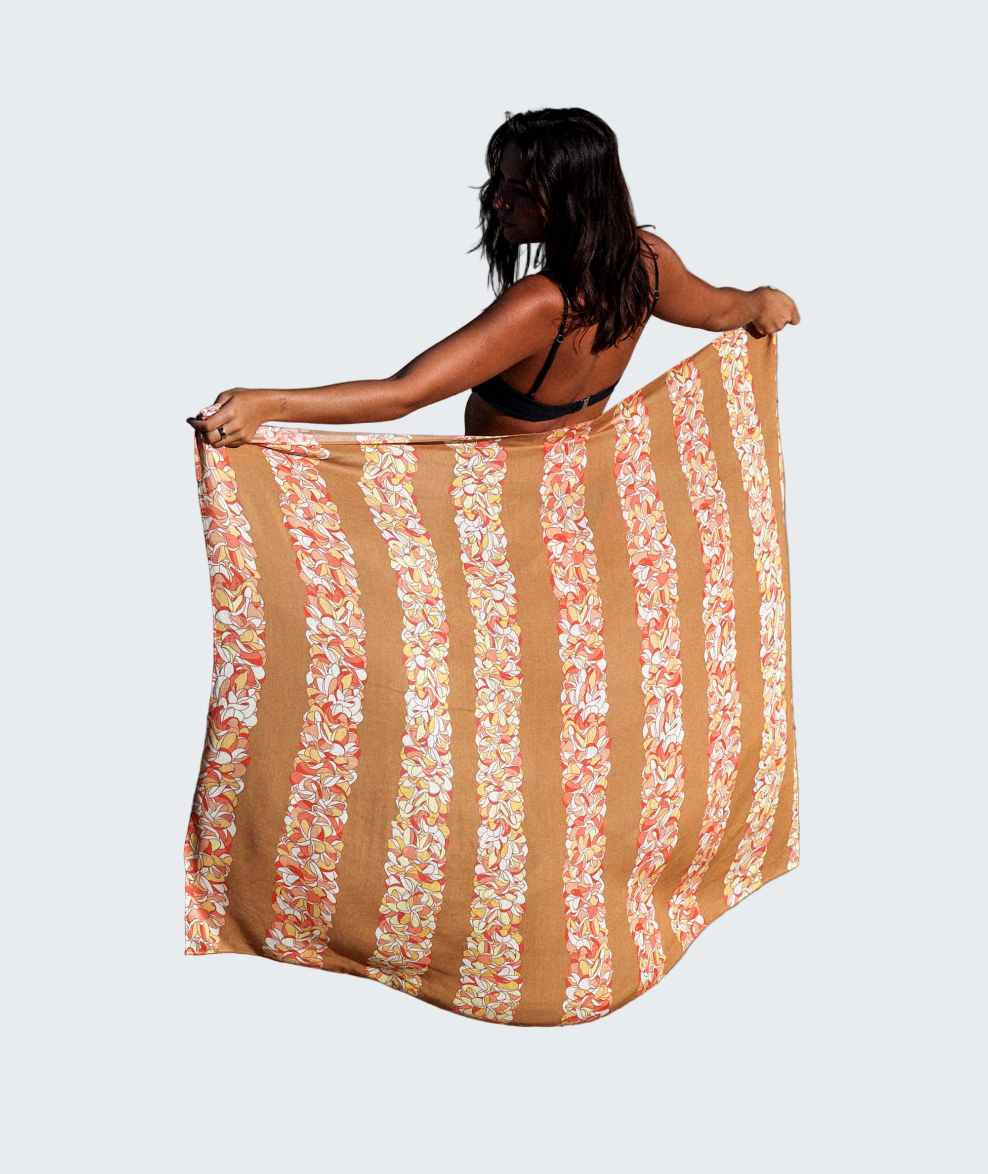 Woman on a beach holding a patterned towel