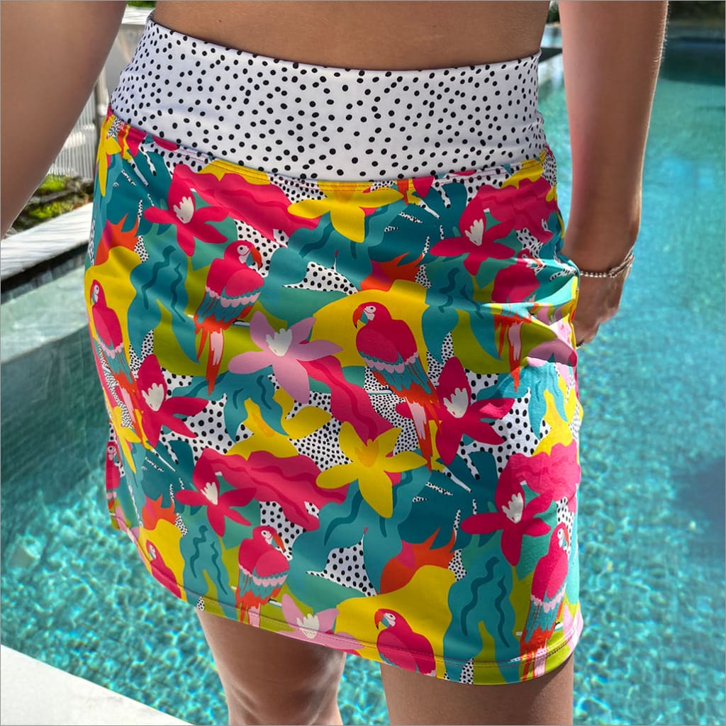 Colorful floral skirt with a polka dot waistband worn by a person by a pool.