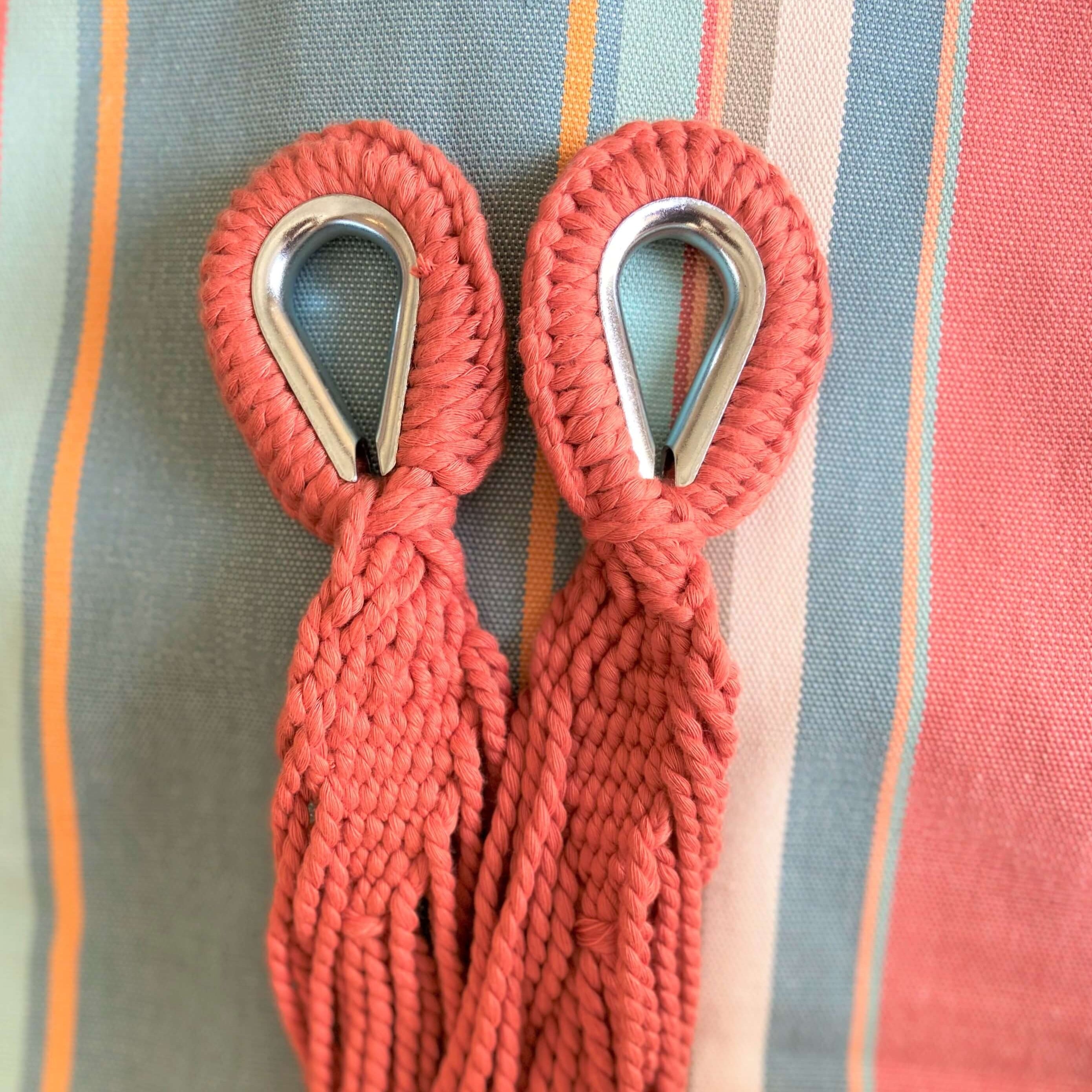 Two red ropes with metal hooks on a striped fabric background